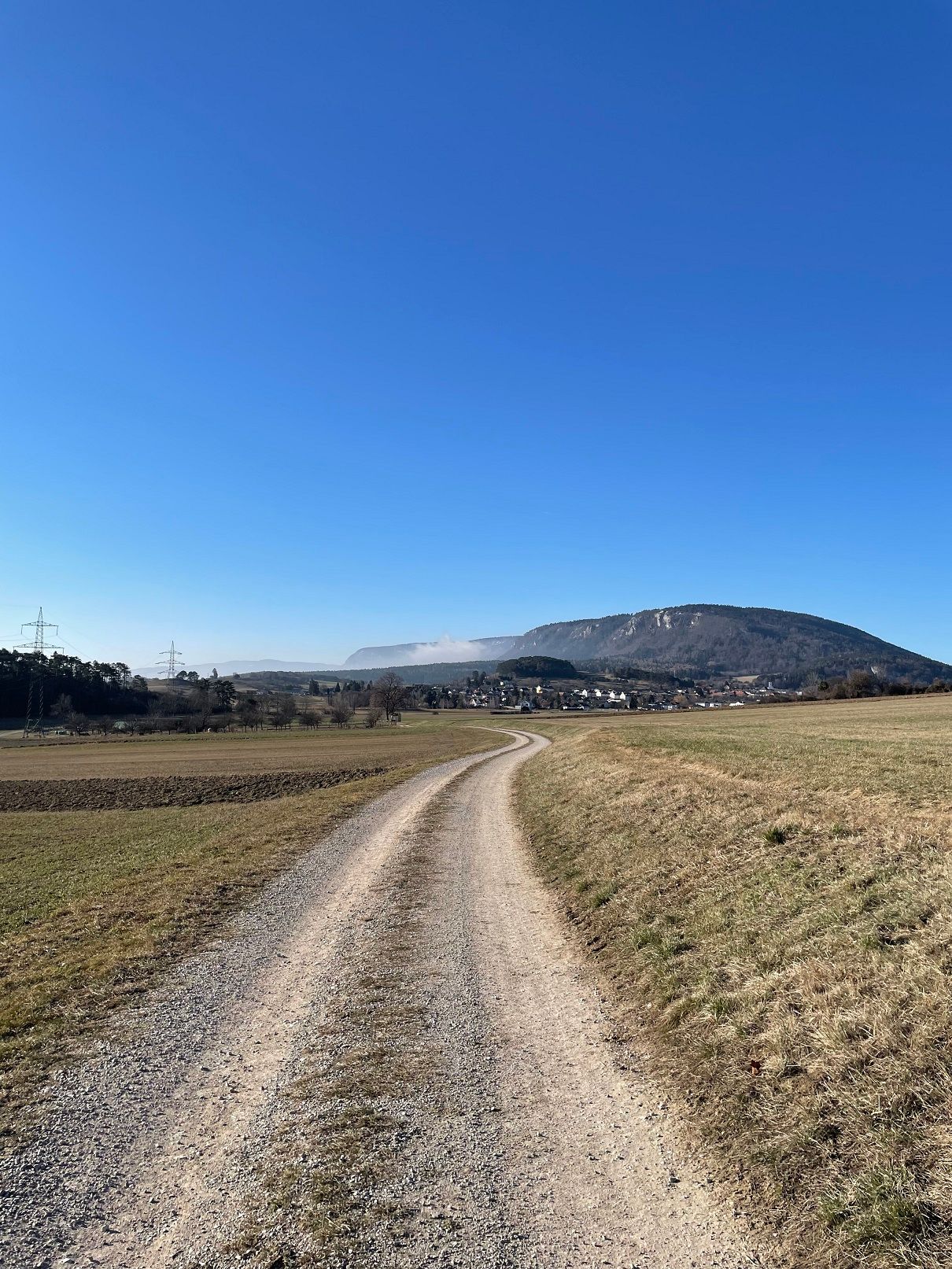 Landscape with dirt road, mountains and blue sky.