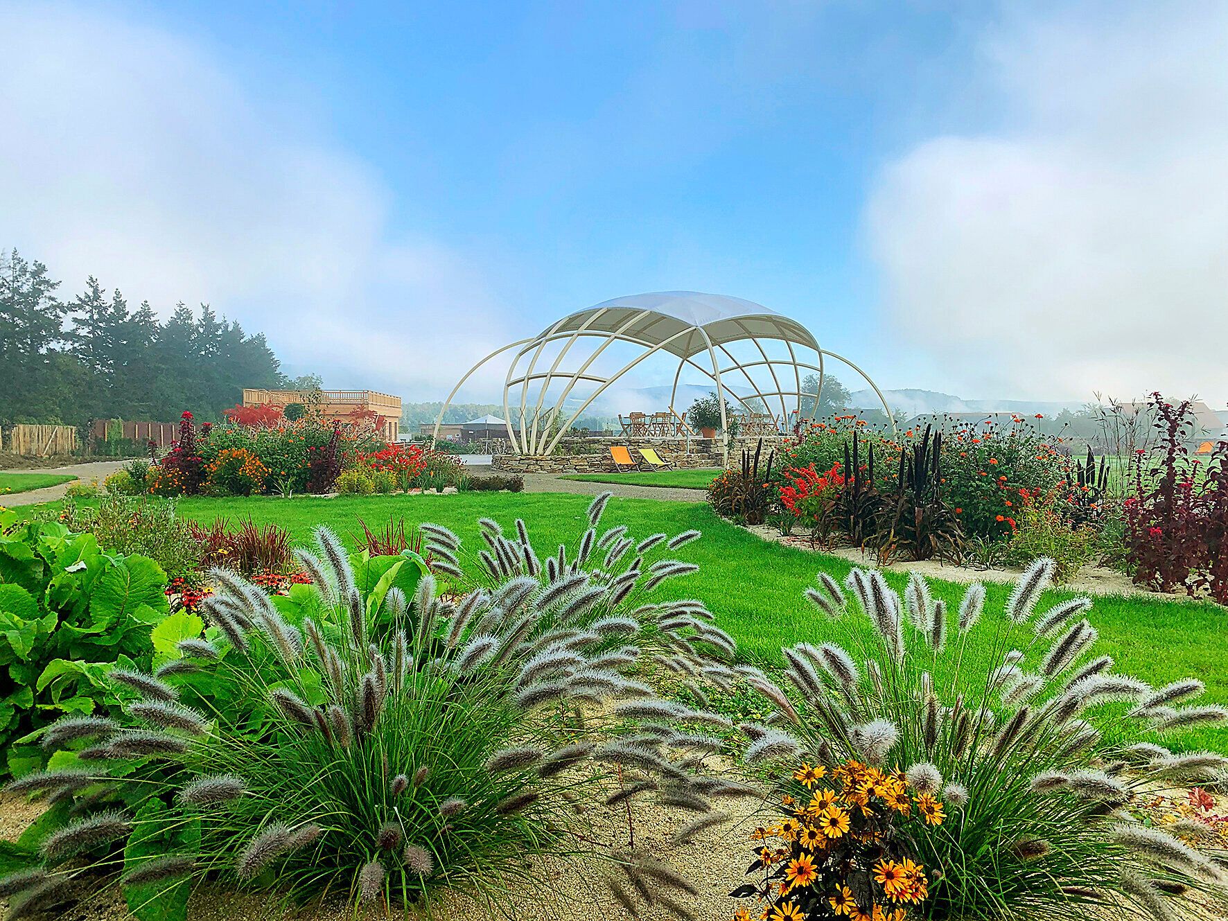 A harmonious garden unfolds its colorful splendor under a bright blue sky. The rolling hills and flowering plants invite you to unwind and enjoy the beauty of nature.