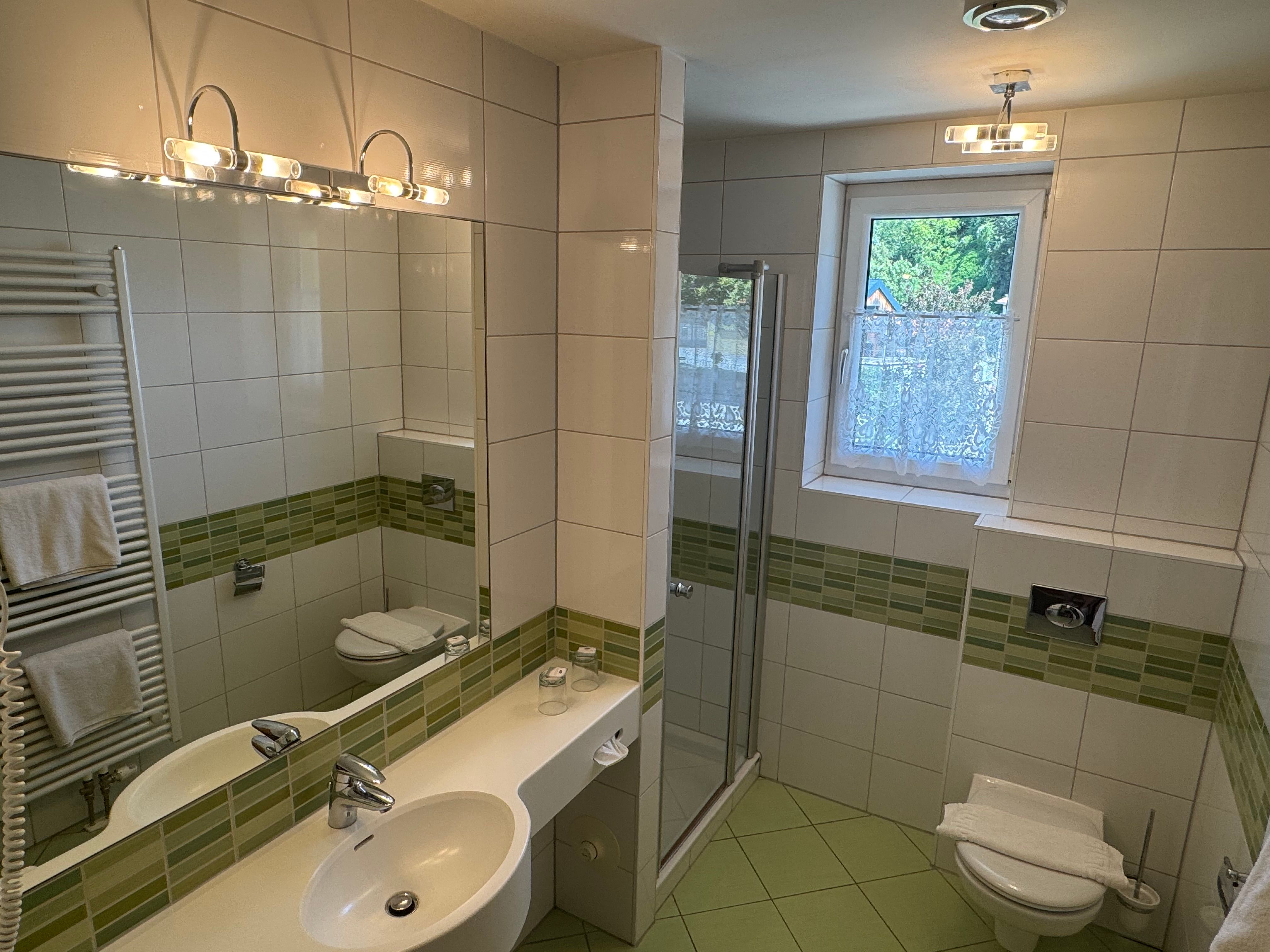 Modern bathroom with green tiles, shower, washbasin and WC.