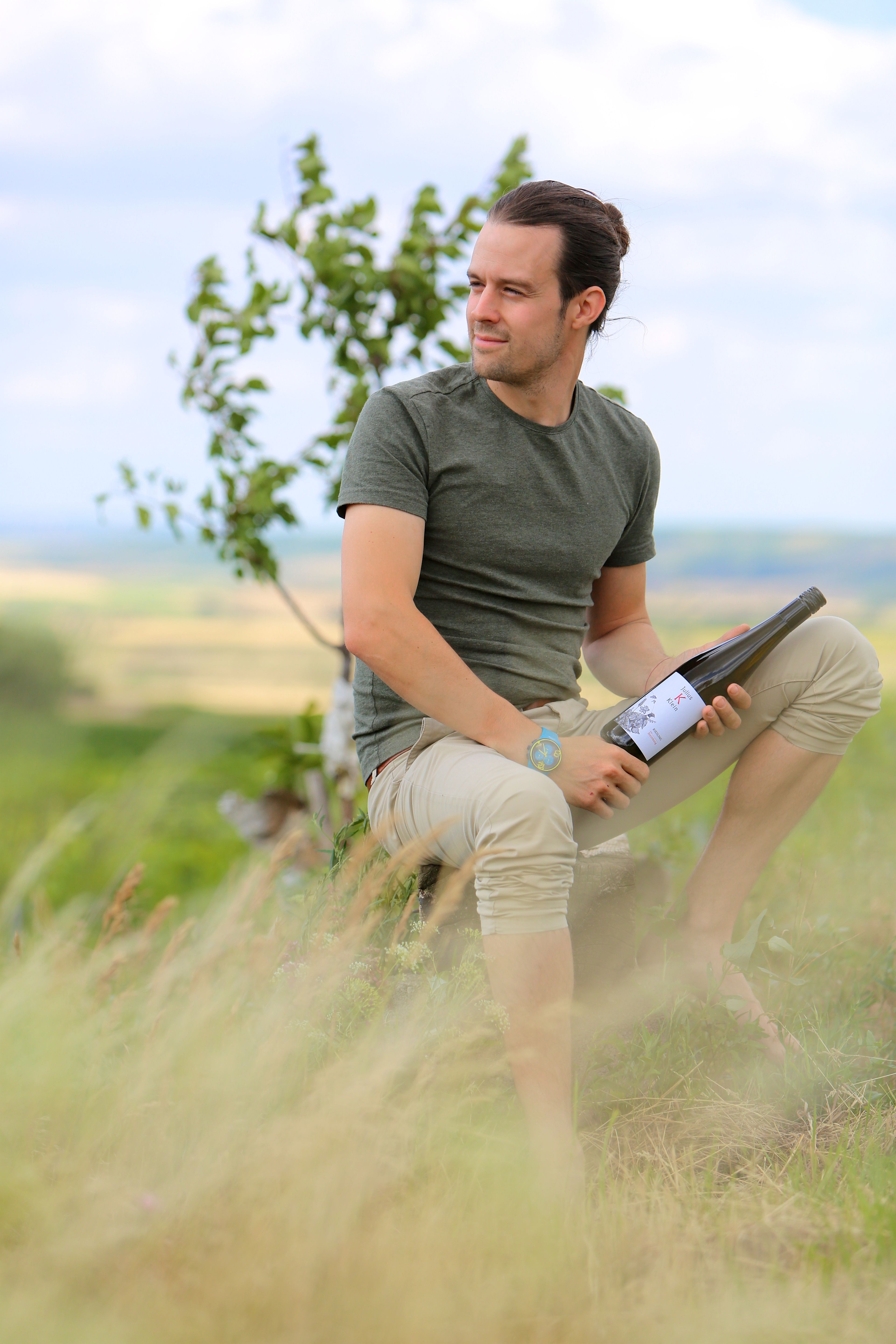 Person sitting outside with a bottle of wine in their hand.