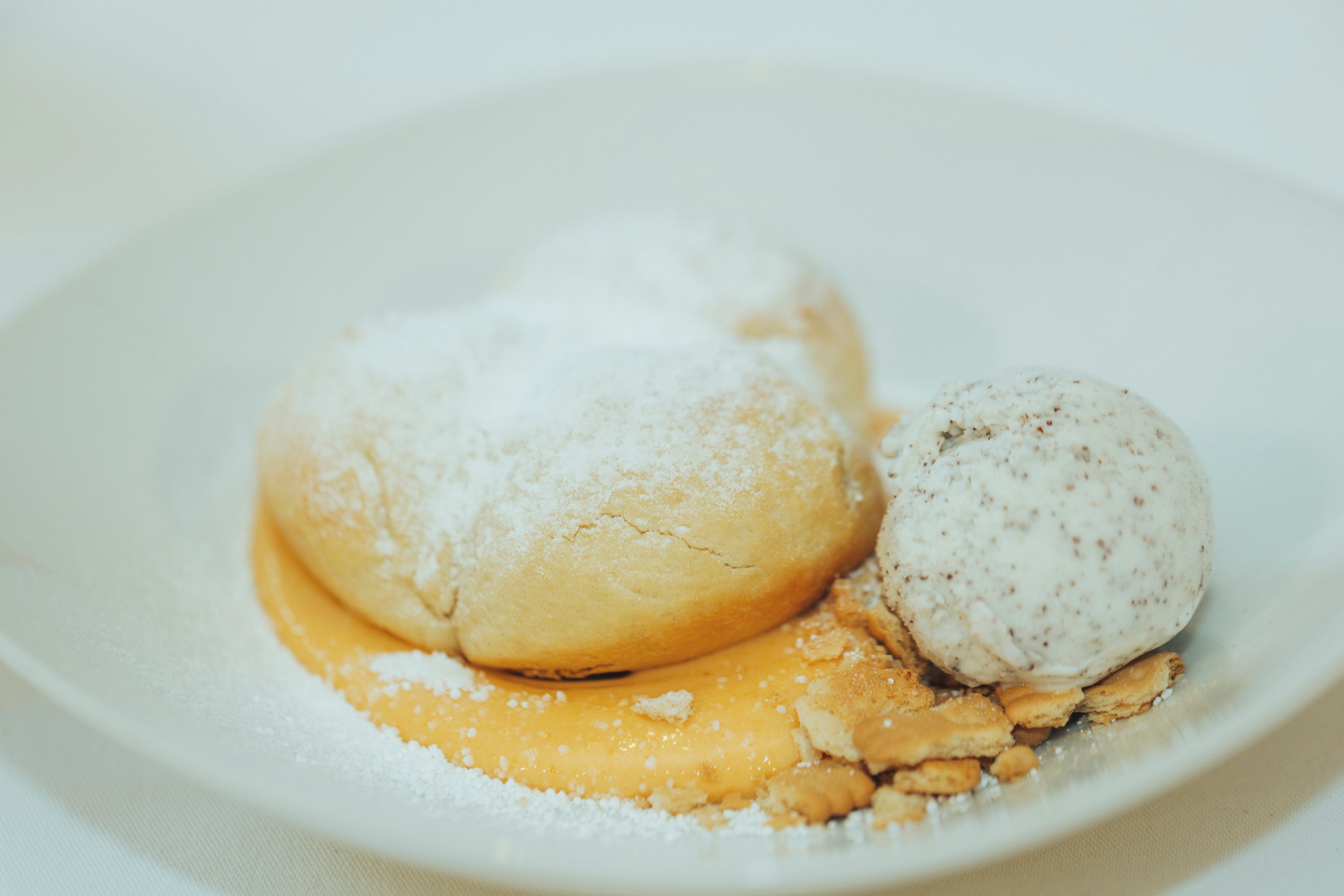 Buchteln with powdered sugar, apricot jam and poppy seed ice cream on a plate.