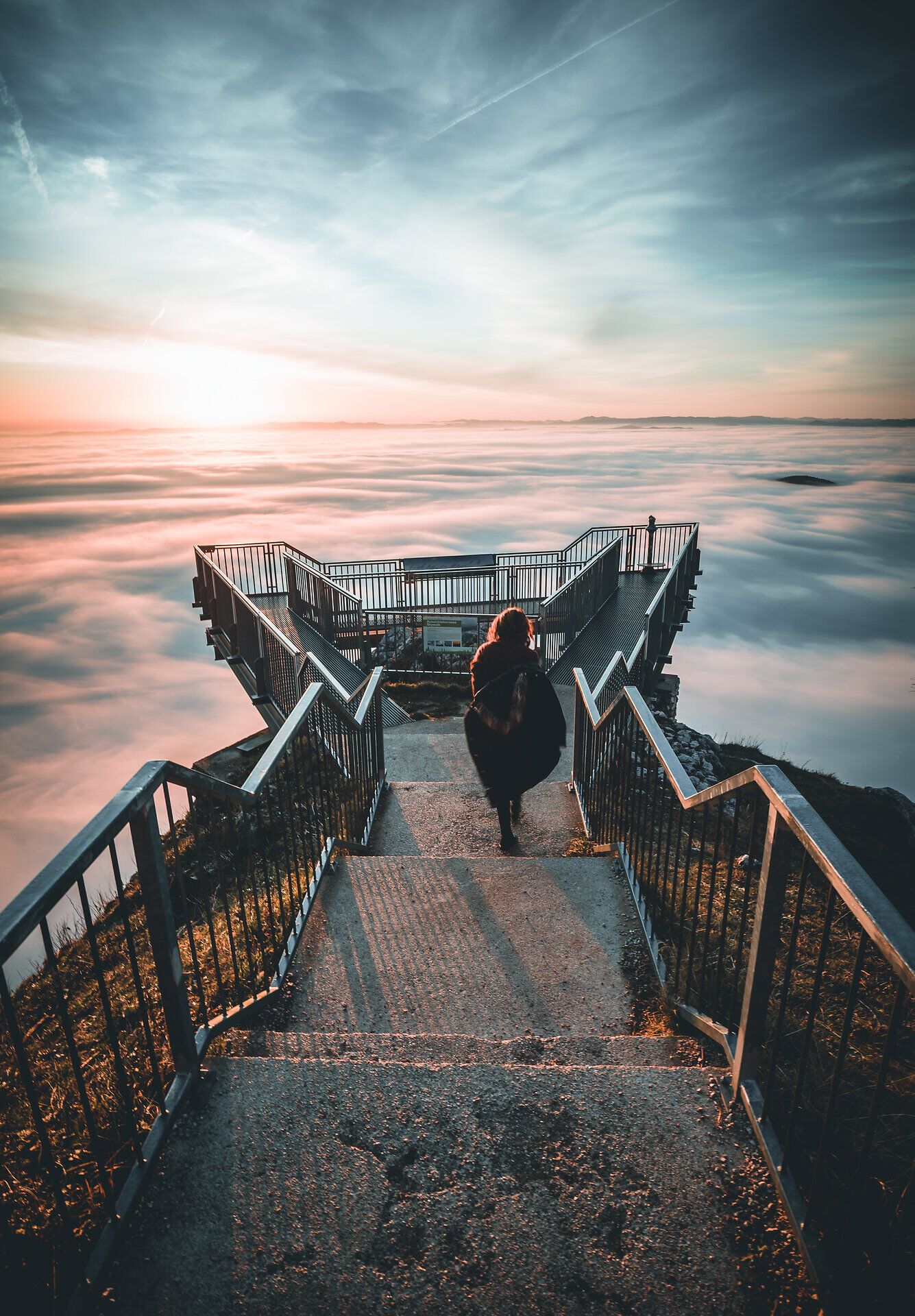 Die Aussichtsplattform bietet einen atemberaubenden Blick über das Nebelmeer, das sanft die Landschaft umhüllt. Die kühle Morgenluft und das sanfte Licht der aufgehenden Sonne schaffen eine magische Atmosphäre, die zum Verweilen einlädt.