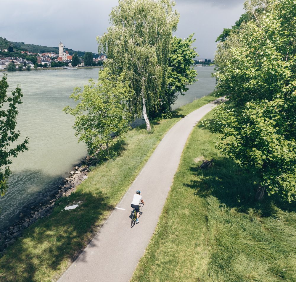 Ein malerischer Radweg schlängelt sich entlang der Donau, umgeben von üppigem Grün und sanften Hügeln. Die ruhige Atmosphäre lädt dazu ein, die Schönheit der Natur zu genießen und die frische Luft zu atmen. Ideal für einen entspannten Ausflug in die idyllische Landschaft Niederösterreichs.