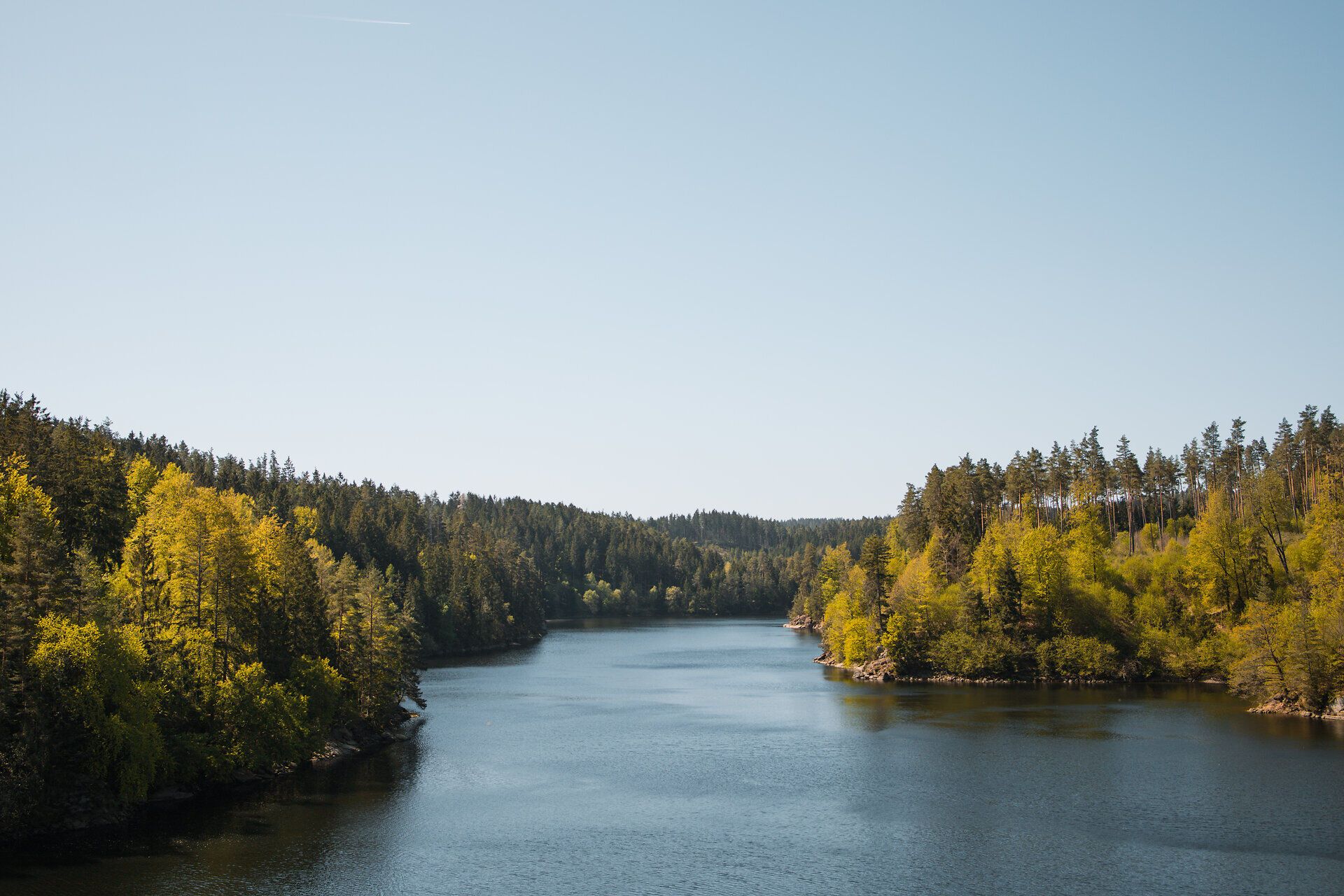 The gentle waves of the Ottenstein reservoir reflect the lush green landscape while the sun shines in the clear sky. Surrounded by dense forests and rolling hills, this place invites you to enjoy the tranquillity of nature and experience the fresh air while cycling.