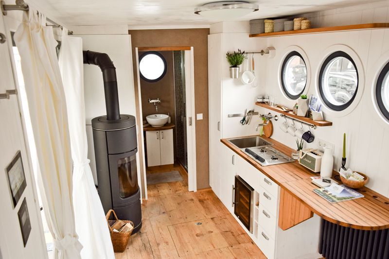 Interior view of a caravan with kitchen, wood-burning stove and bathroom.