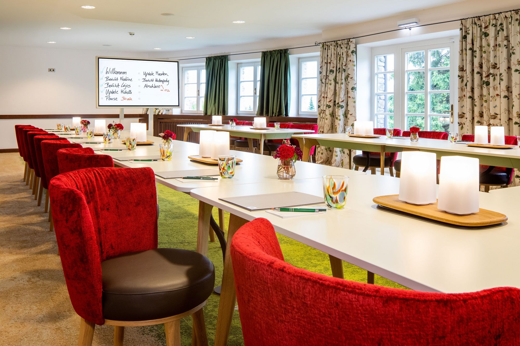 Elegant seminar room with red chairs and white tables.