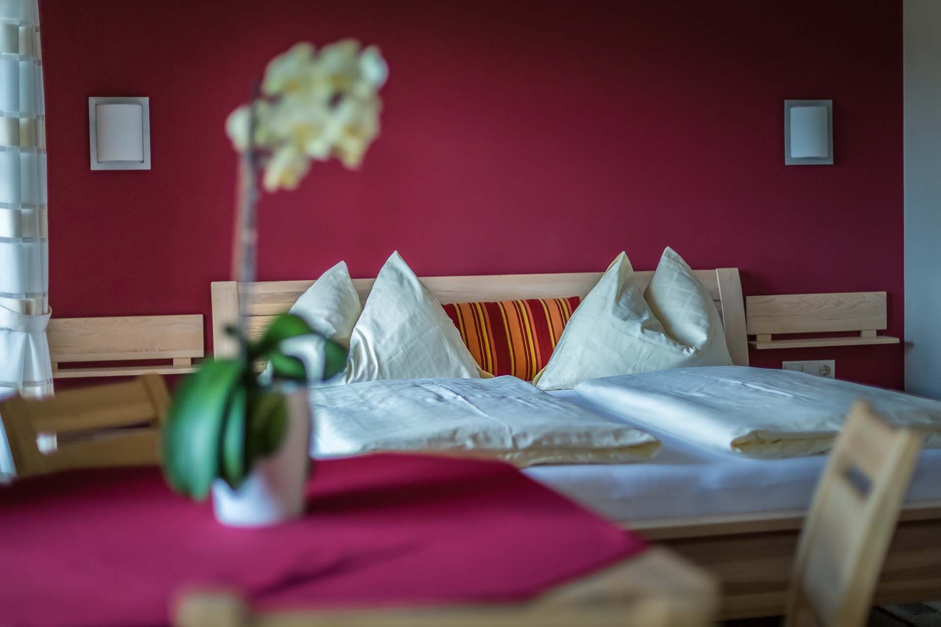 Cozy bedroom with red wall, wooden bed and pillows.