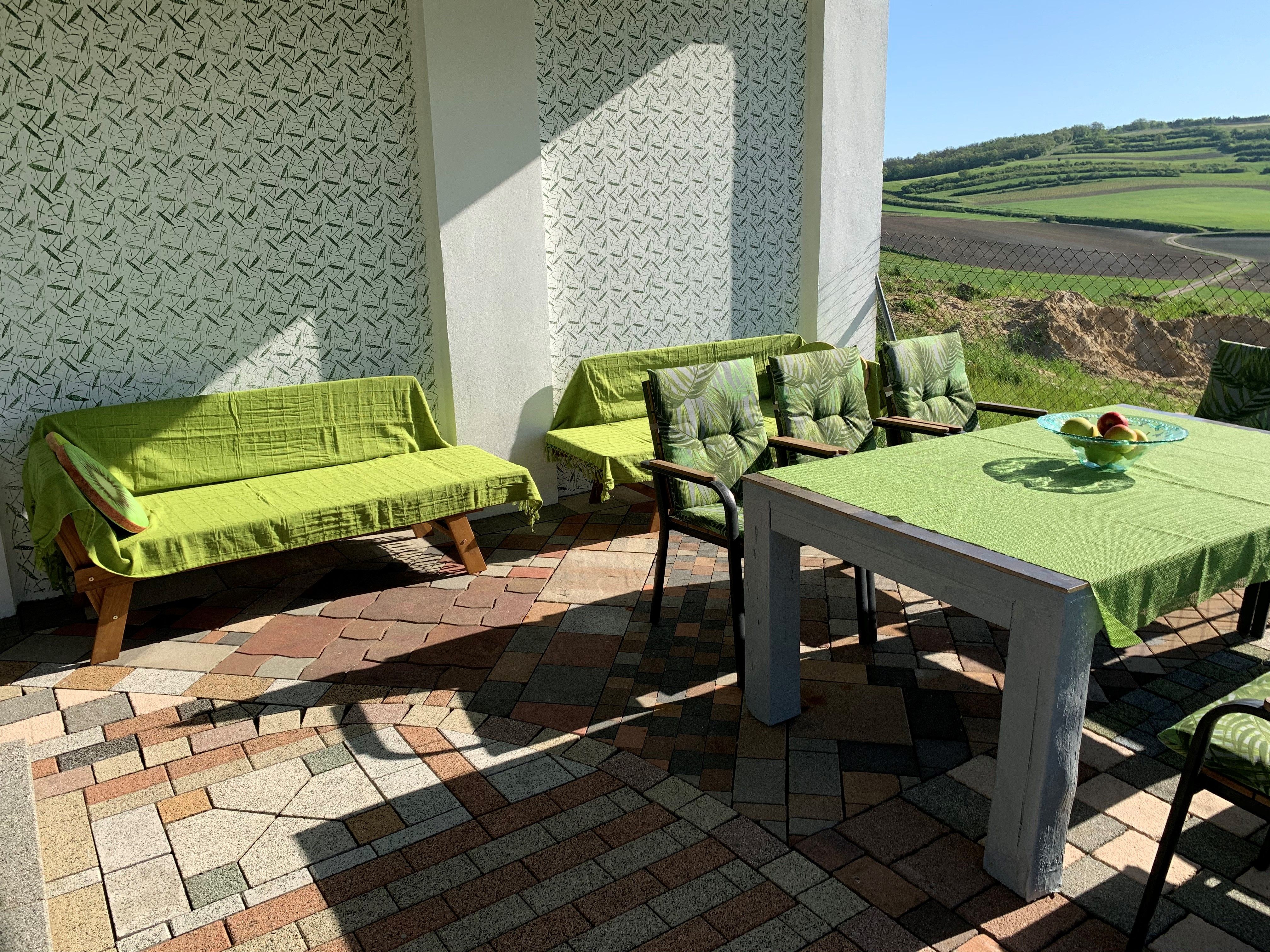Terrace with green furniture and view of fields.