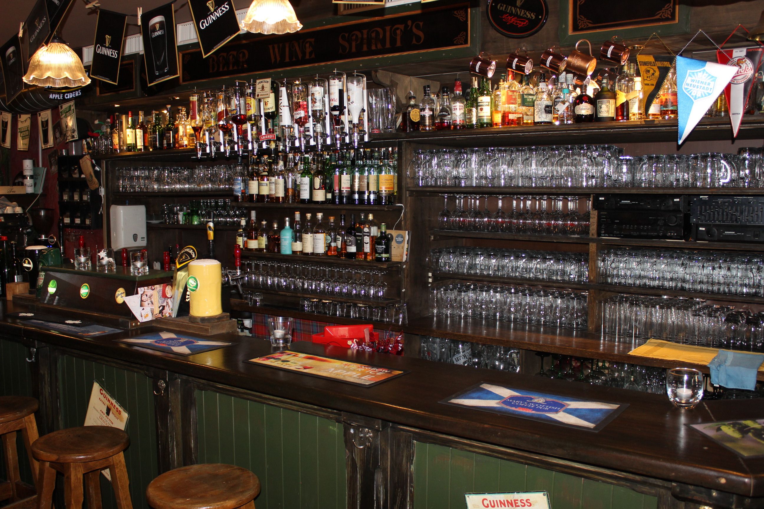 A bar with a large selection of whisky bottles and glasses on shelves.