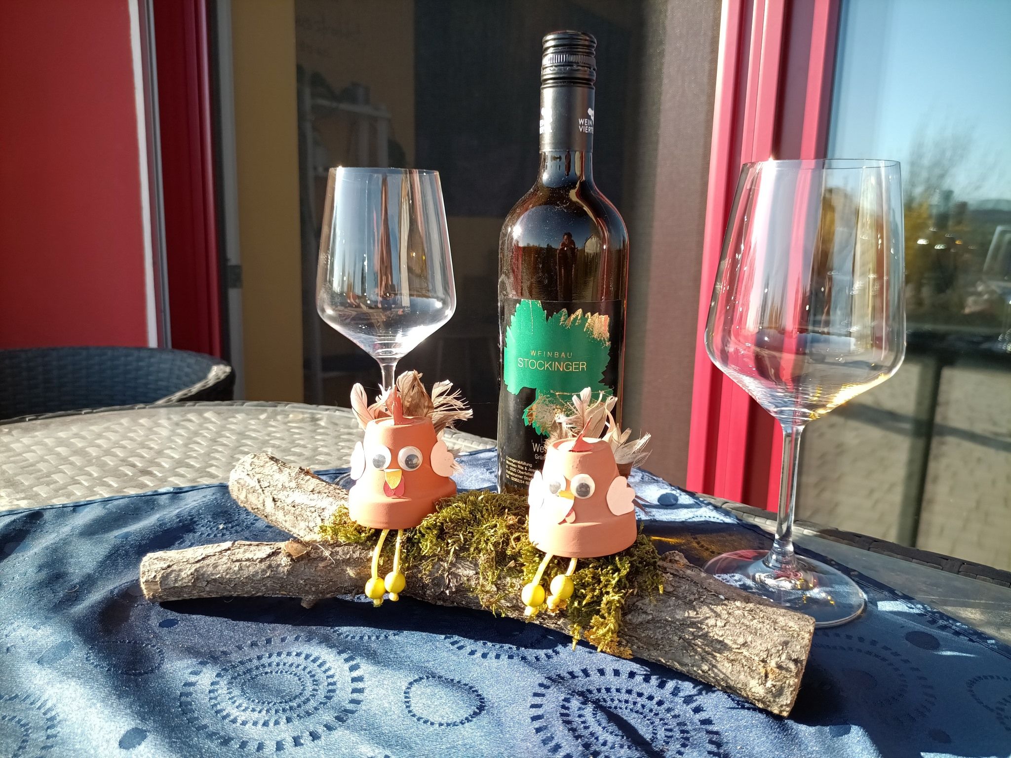 Wine bottle with two empty glasses and decorative figures on a table.