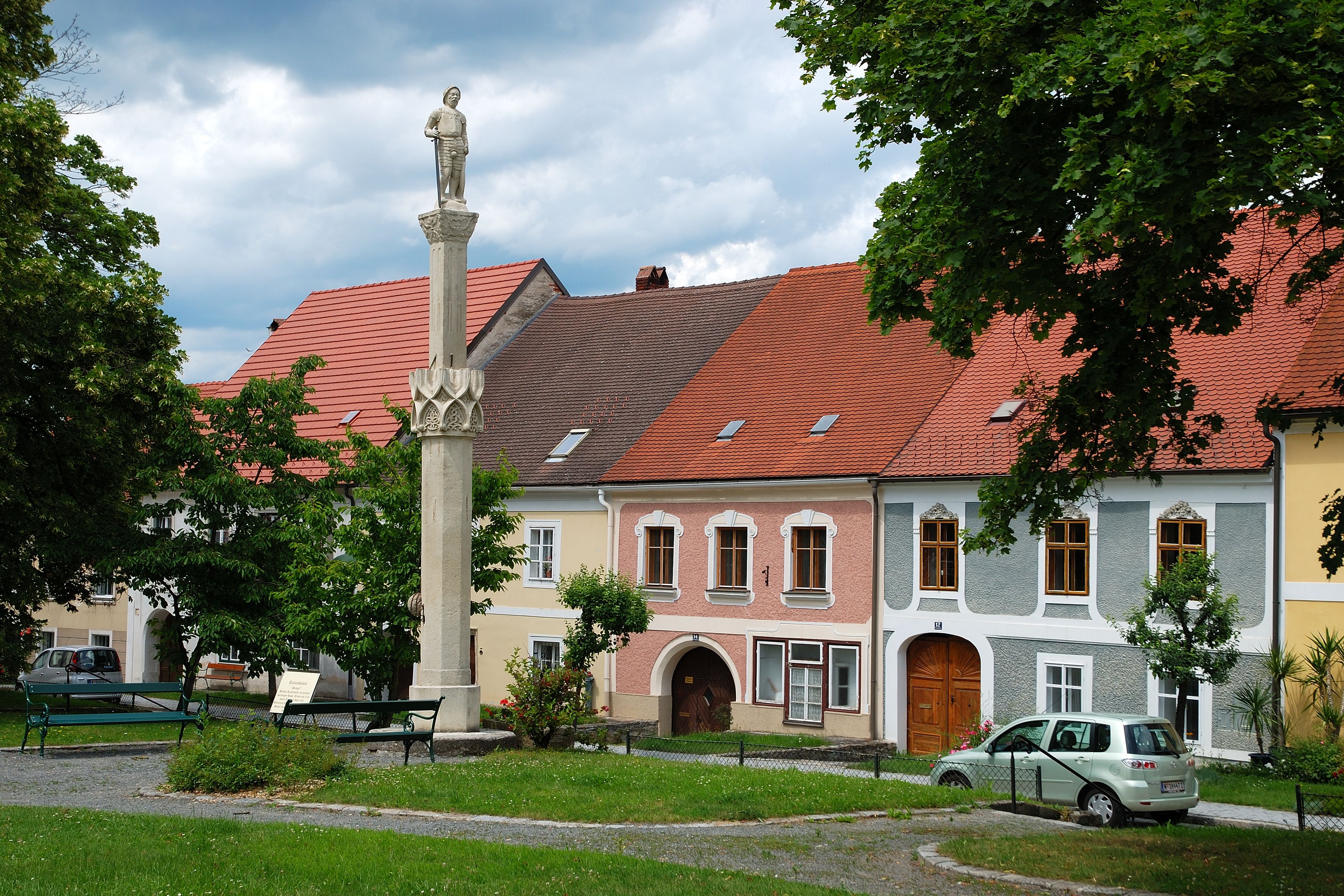 Statue on a pillar in front of colorful houses in Drosendorf-Zissersdorf.