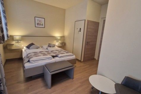 Hotel room with double bed, wooden floor and modern furnishings.