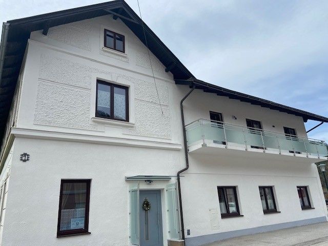 Two-story white house with balcony and several windows.
