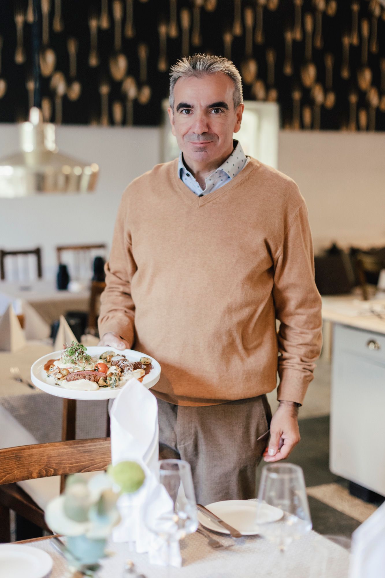 A man in a restaurant holds a plate of food in his hand.