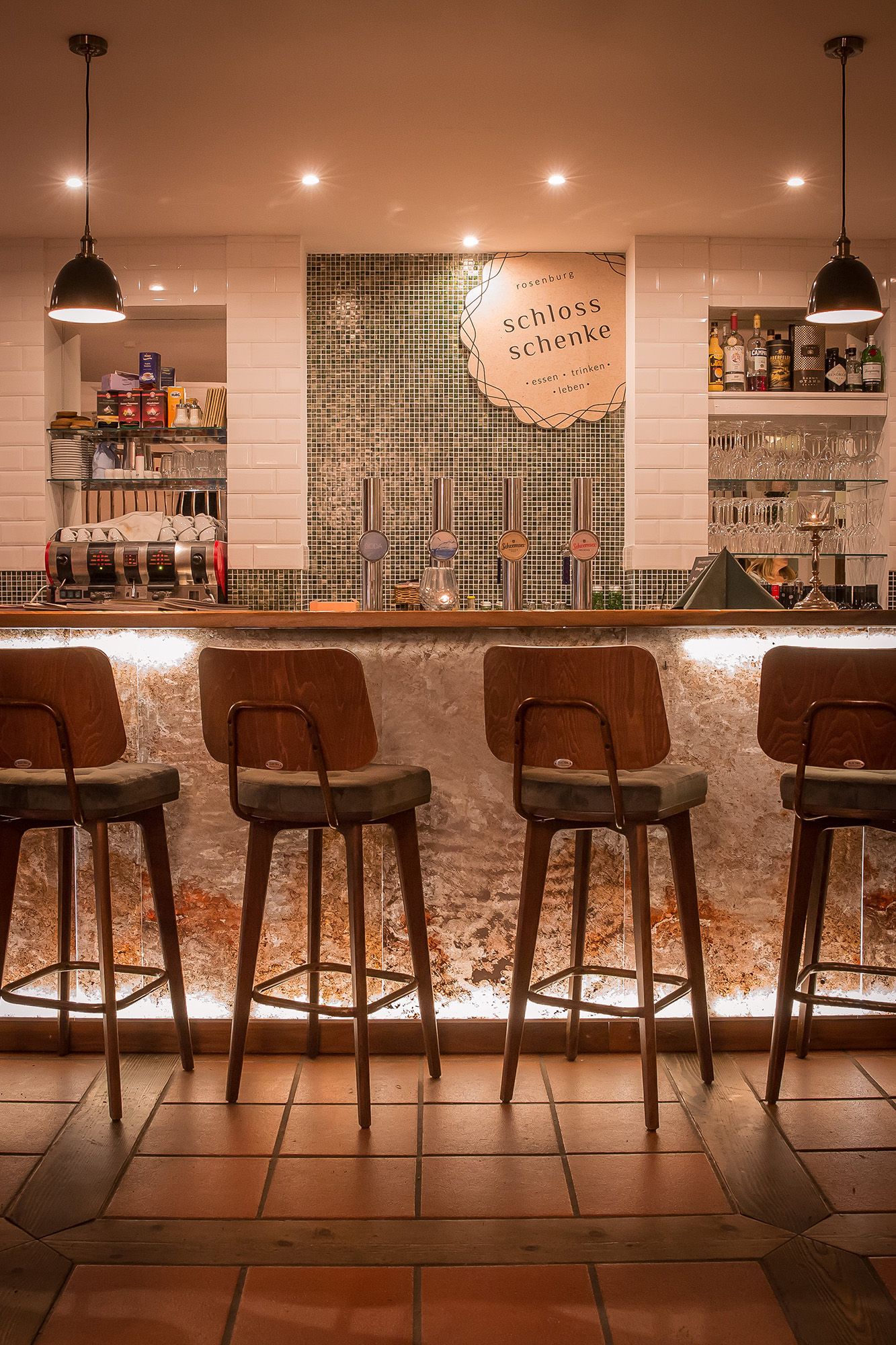 Interior view of a stylish bar with wooden chairs and illuminated counter.