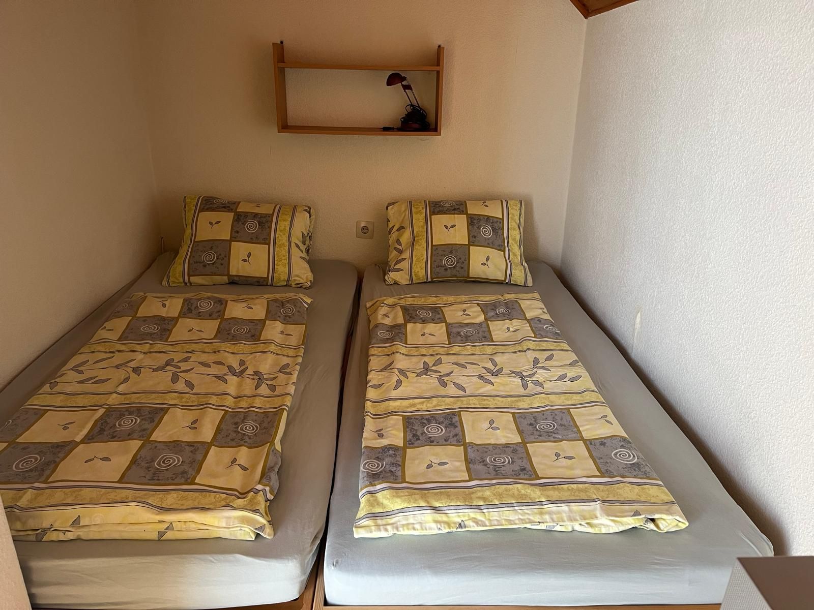 Two single beds with patterned comforters in a small room.