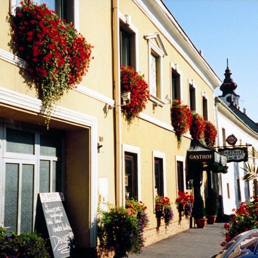 A traditional inn with a yellow façade and red flowers on the windows.