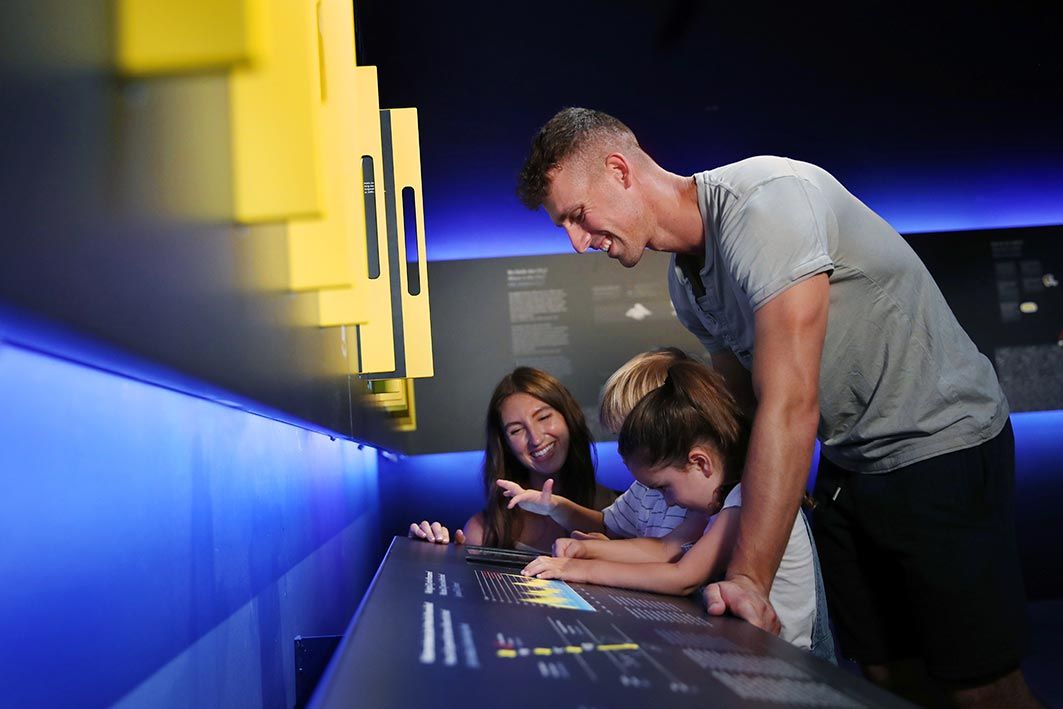 A family interacts with an exhibition in a museum.