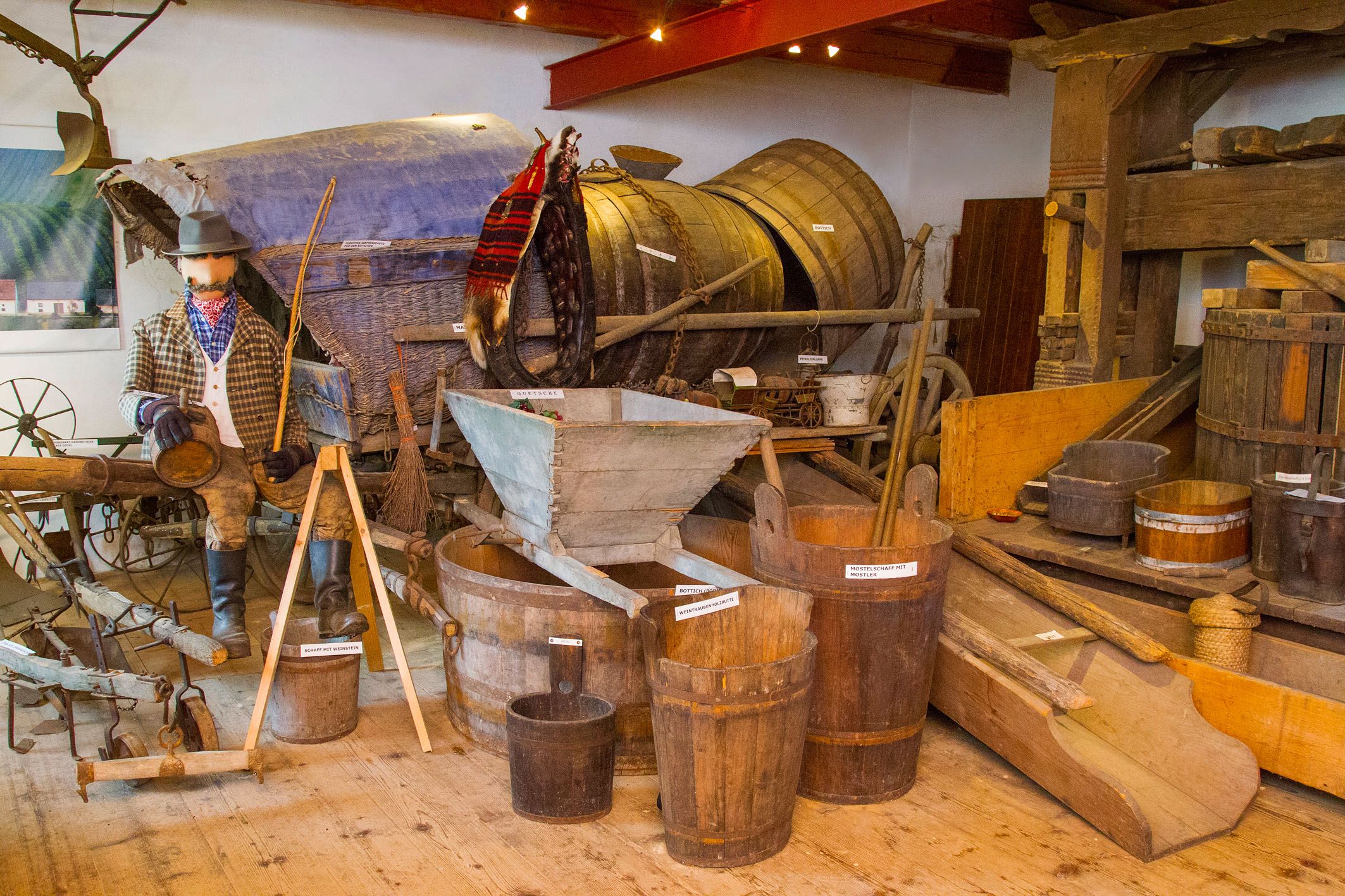Exhibition of old agricultural equipment and wooden barrels.
