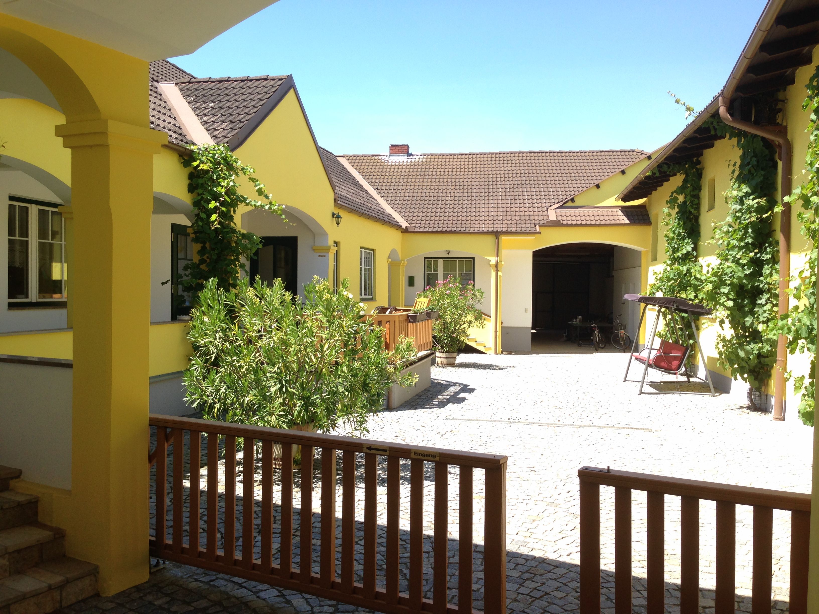 Inner courtyard of a yellow vineyard with plants and a swing.