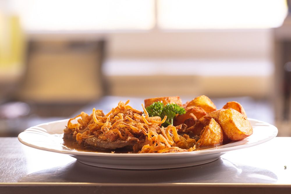 A plate of roast onions, fried onions and roast potatoes.