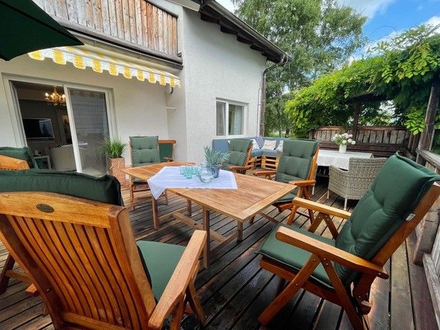 Wooden terrace with table, comfortable chairs and sun protection.