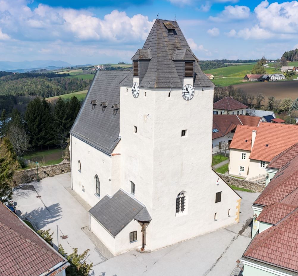 Lichtenegg fortified church with massive clock tower and surrounding buildings.