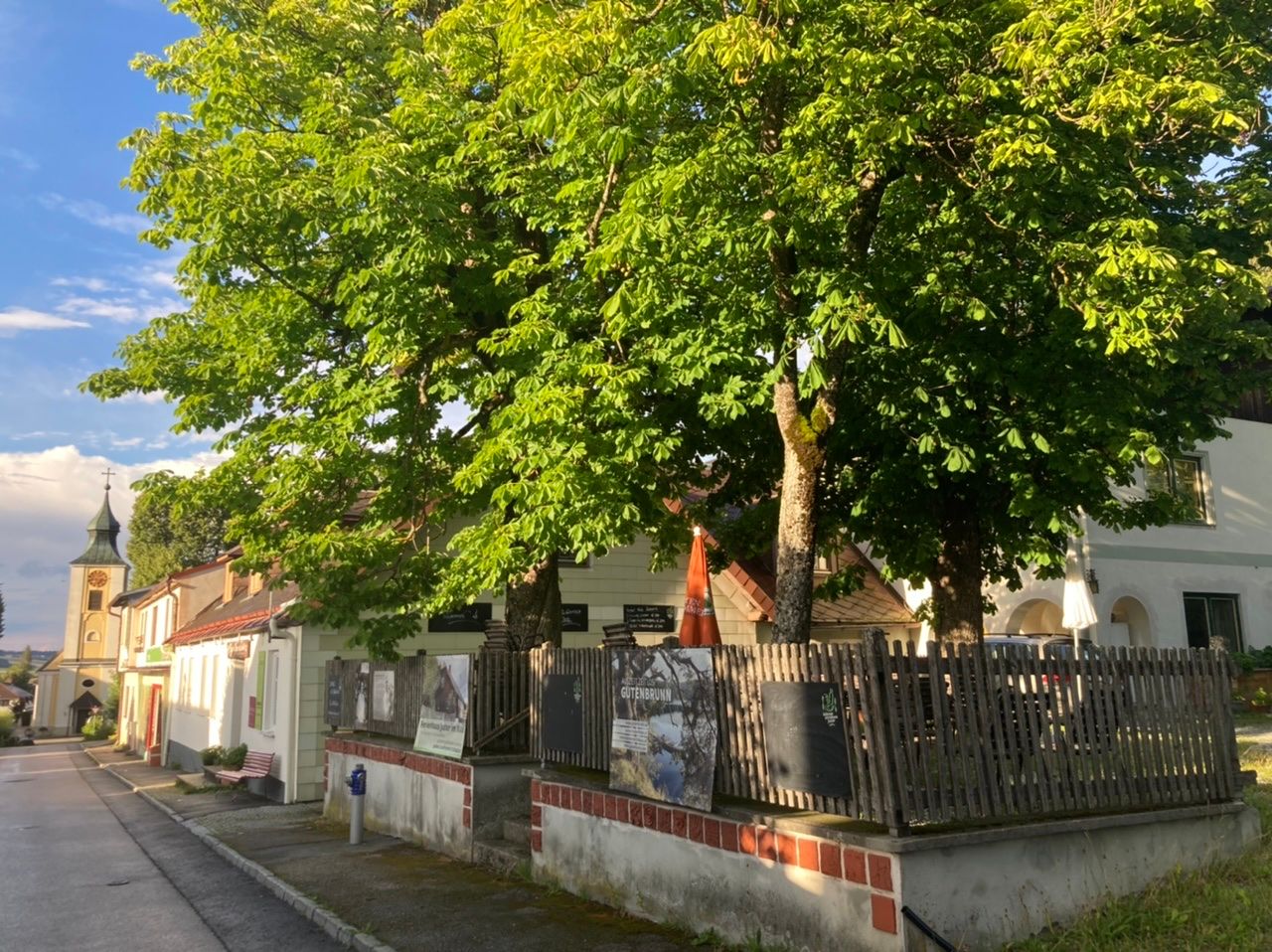 A traditional inn with a chestnut garden and a church in the background.