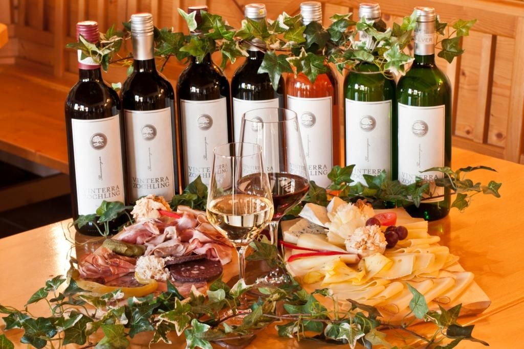 Bottles of wine and cold platters of cheese and sausage on a table.