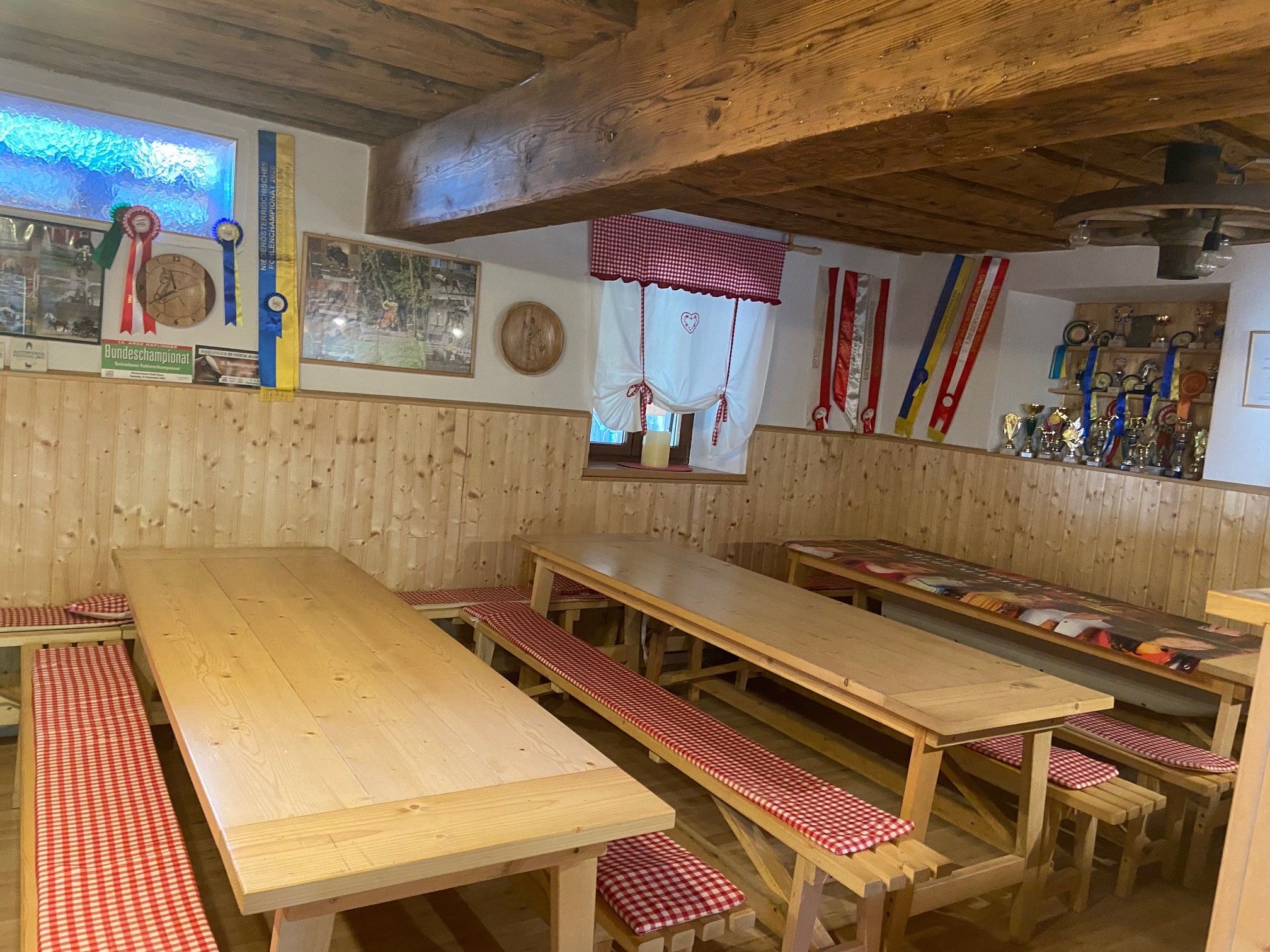 Cozy common room with wooden tables, benches and decorations on the walls.