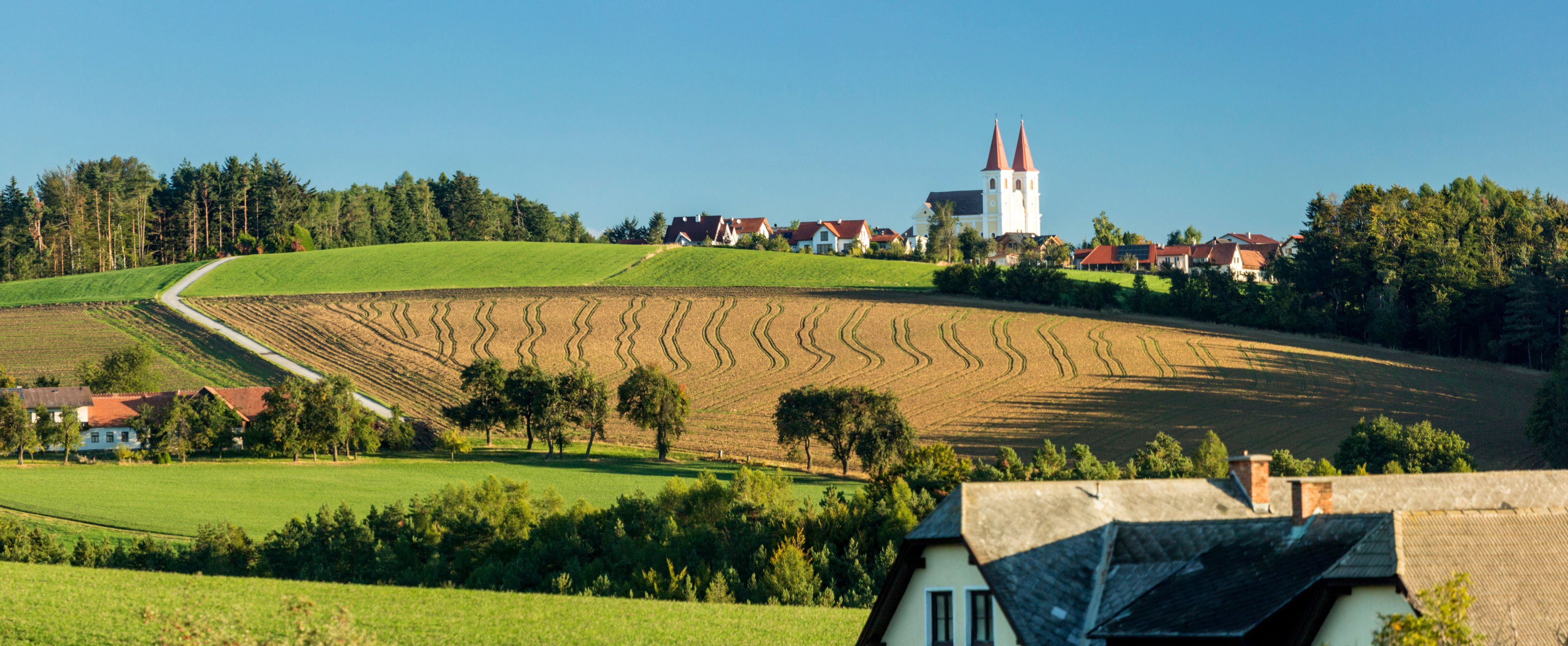 Landscape with the peaks of the Maria Schnee pilgrimage church and fields in Lichtenegg.