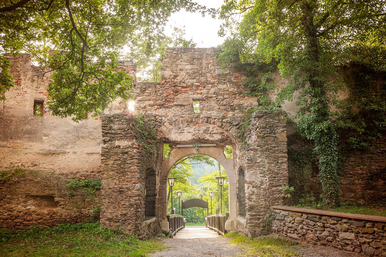 Entrance gate to Gars Castle, surrounded by old stone walls and green vegetation.