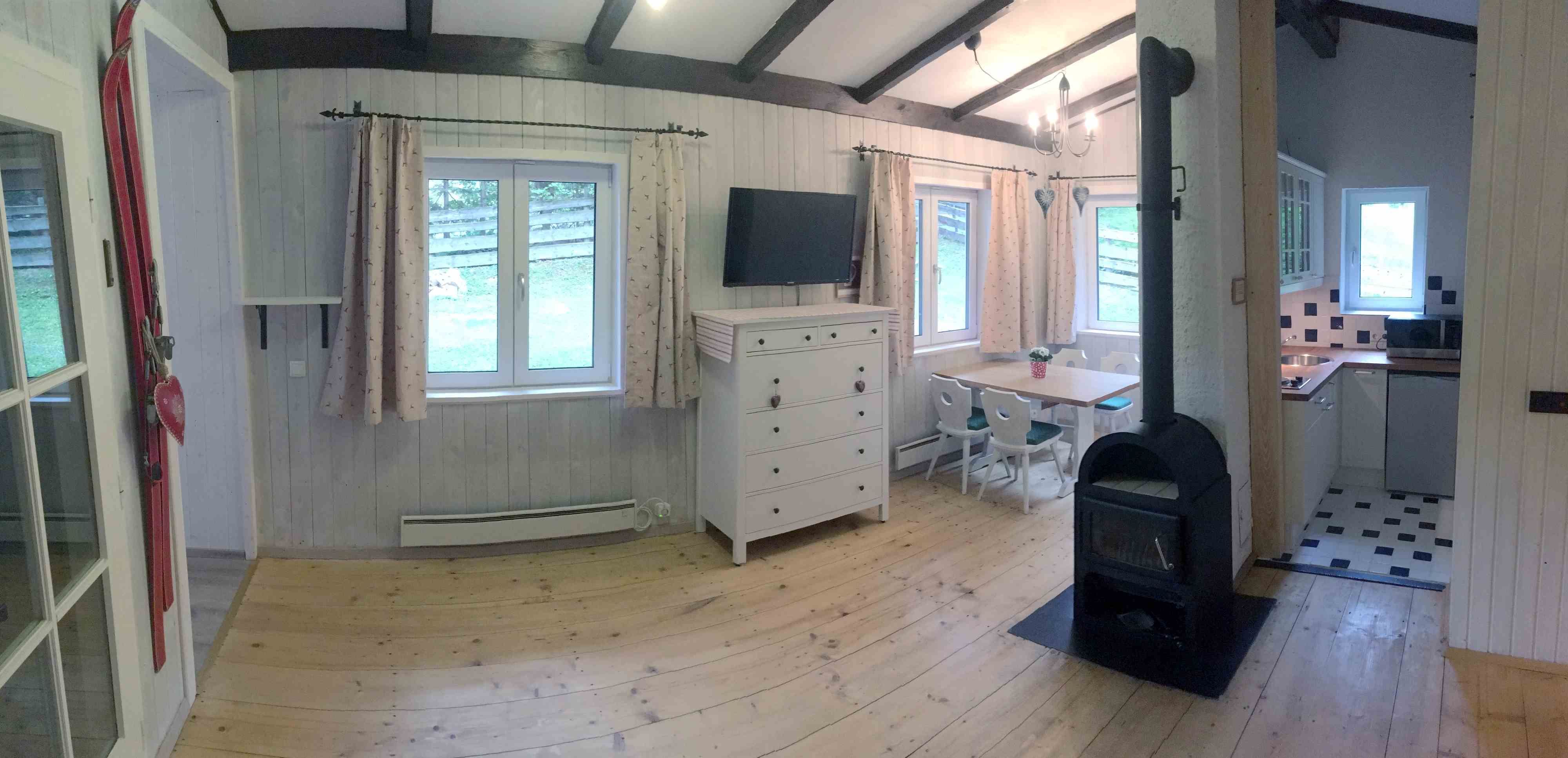 Interior view of a cozy vacation home with wood-burning stove, dining table and kitchen.
