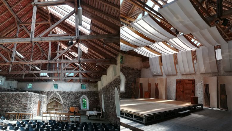 Interior view of a historic building with wooden roof and stage.