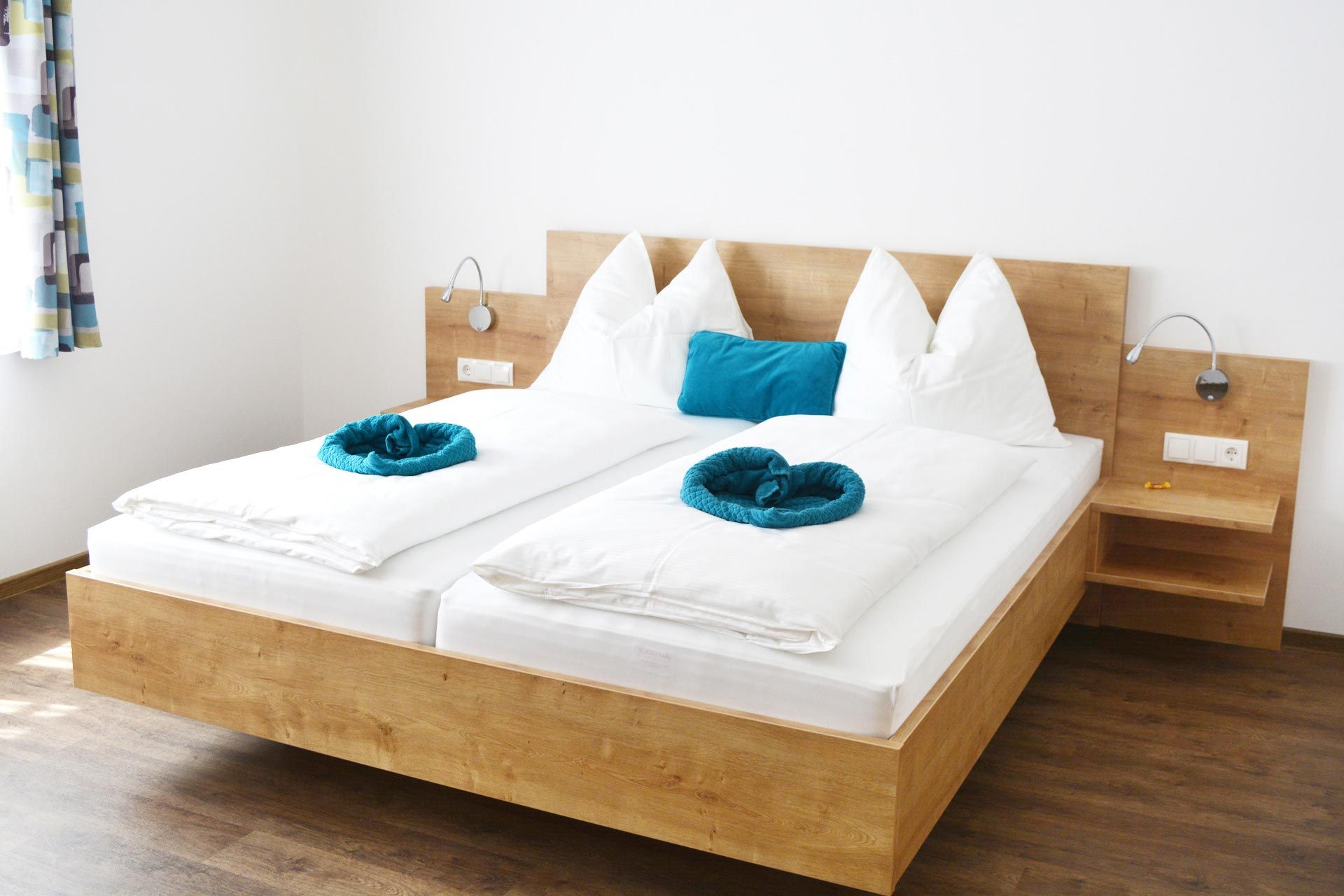 Modern guest room with double bed, white comforters and blue pillows.