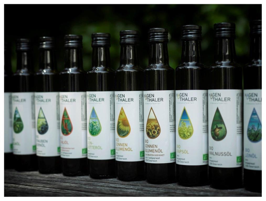Row of Hagenthaler oil bottles on a wooden table.