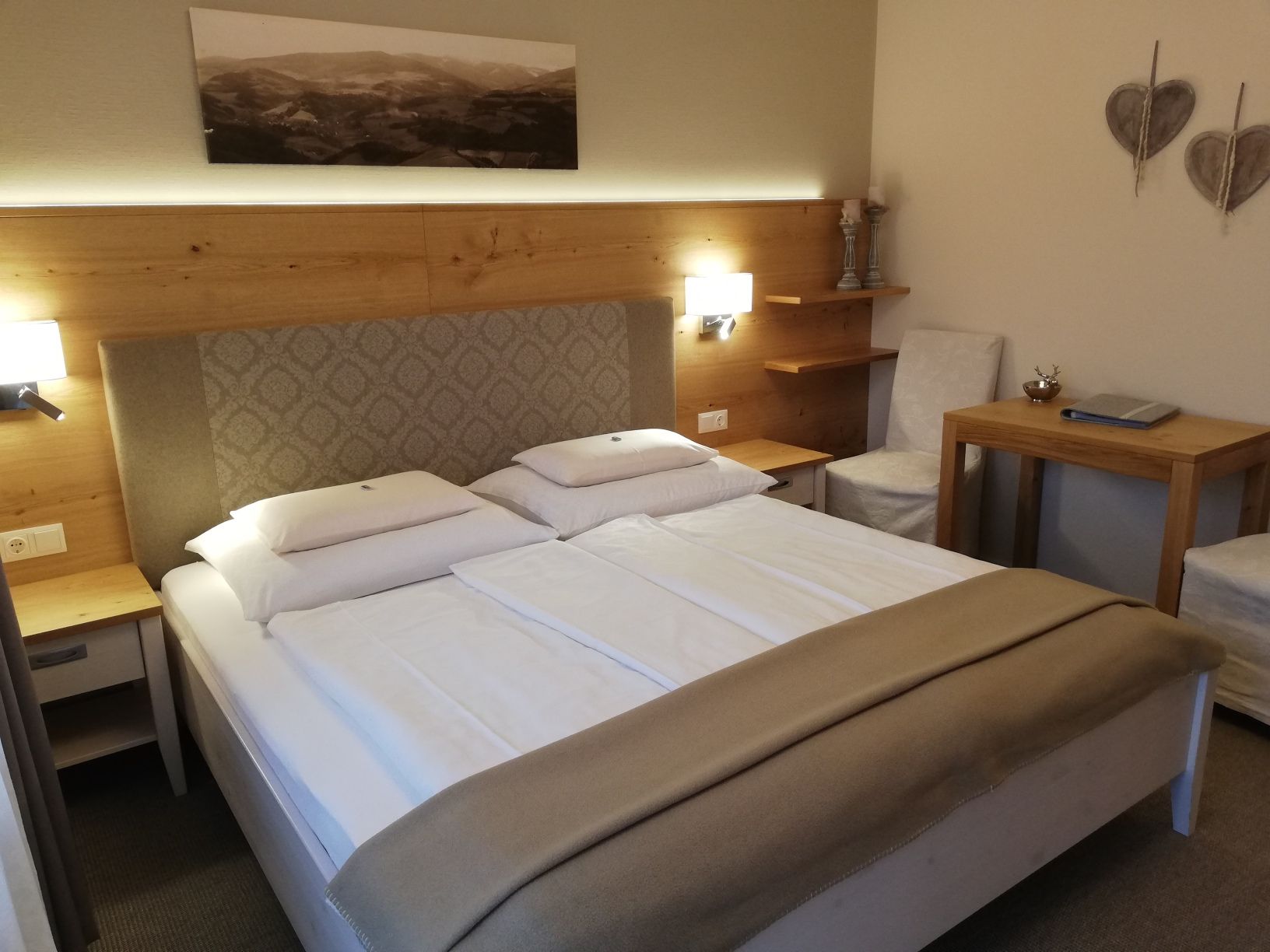 Cozy hotel room with double bed, wooden furniture and wall decoration.
