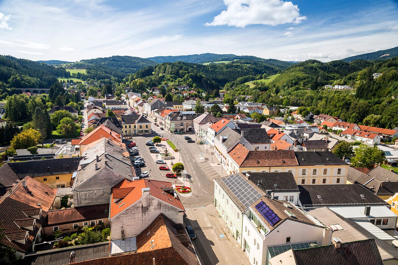Aerial view of Aspang Markt with red roofs and green landscape in the background.