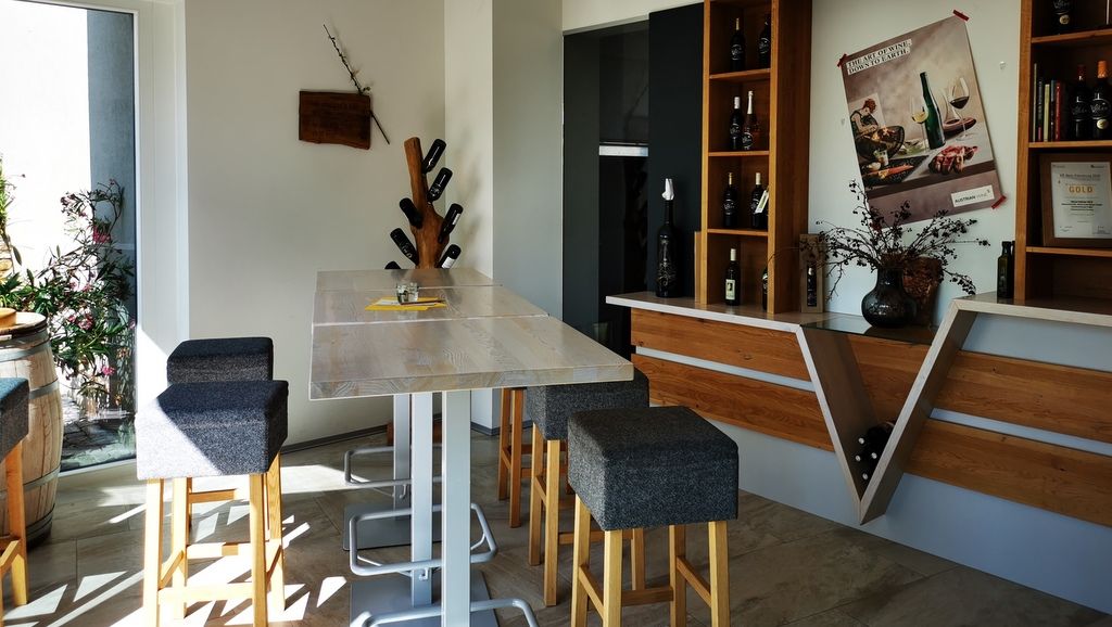 Modern tasting room with wooden table, bar stools and wine racks.