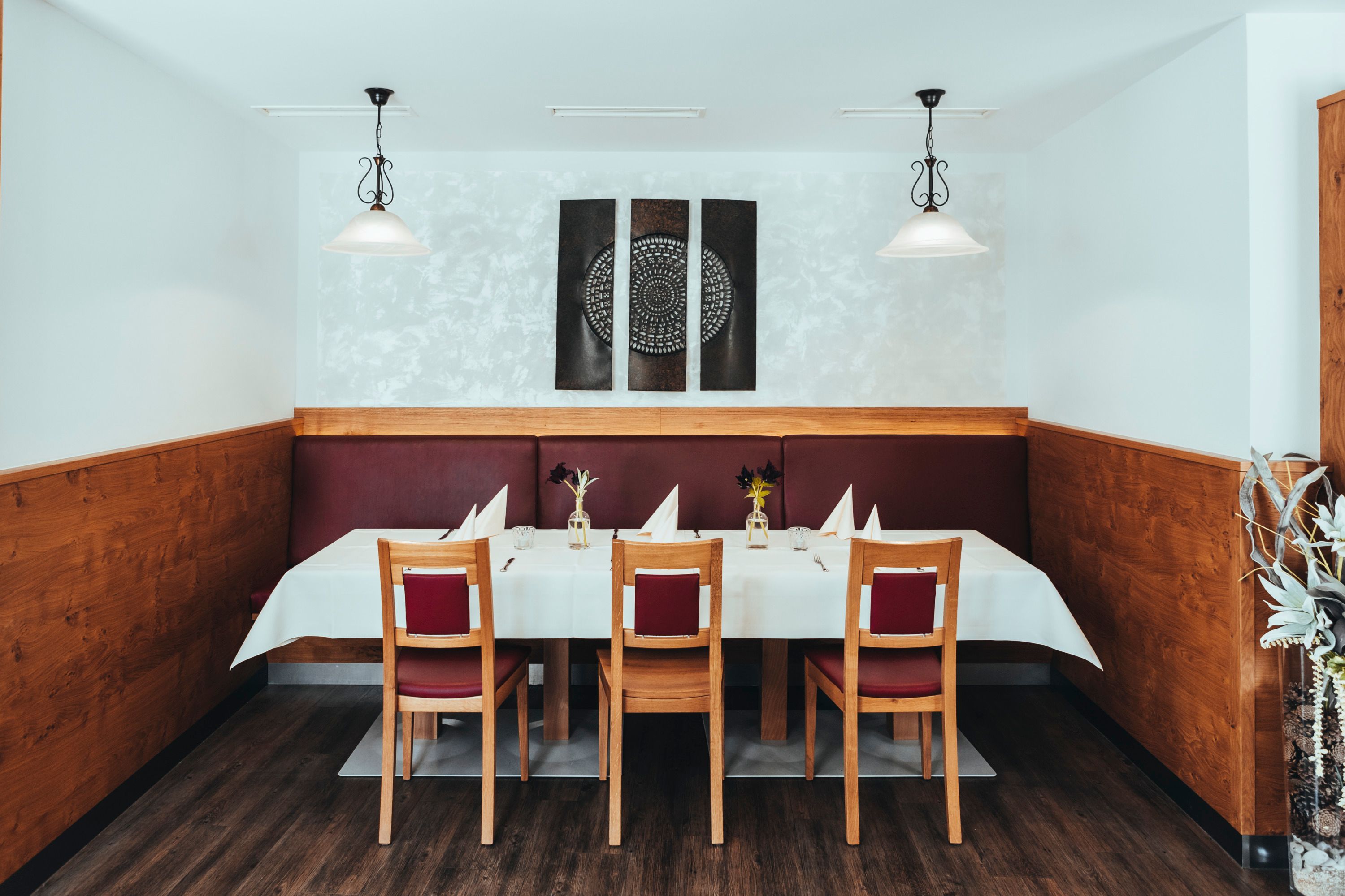 A stylishly laid table in a restaurant with wood paneling and modern art on the wall.