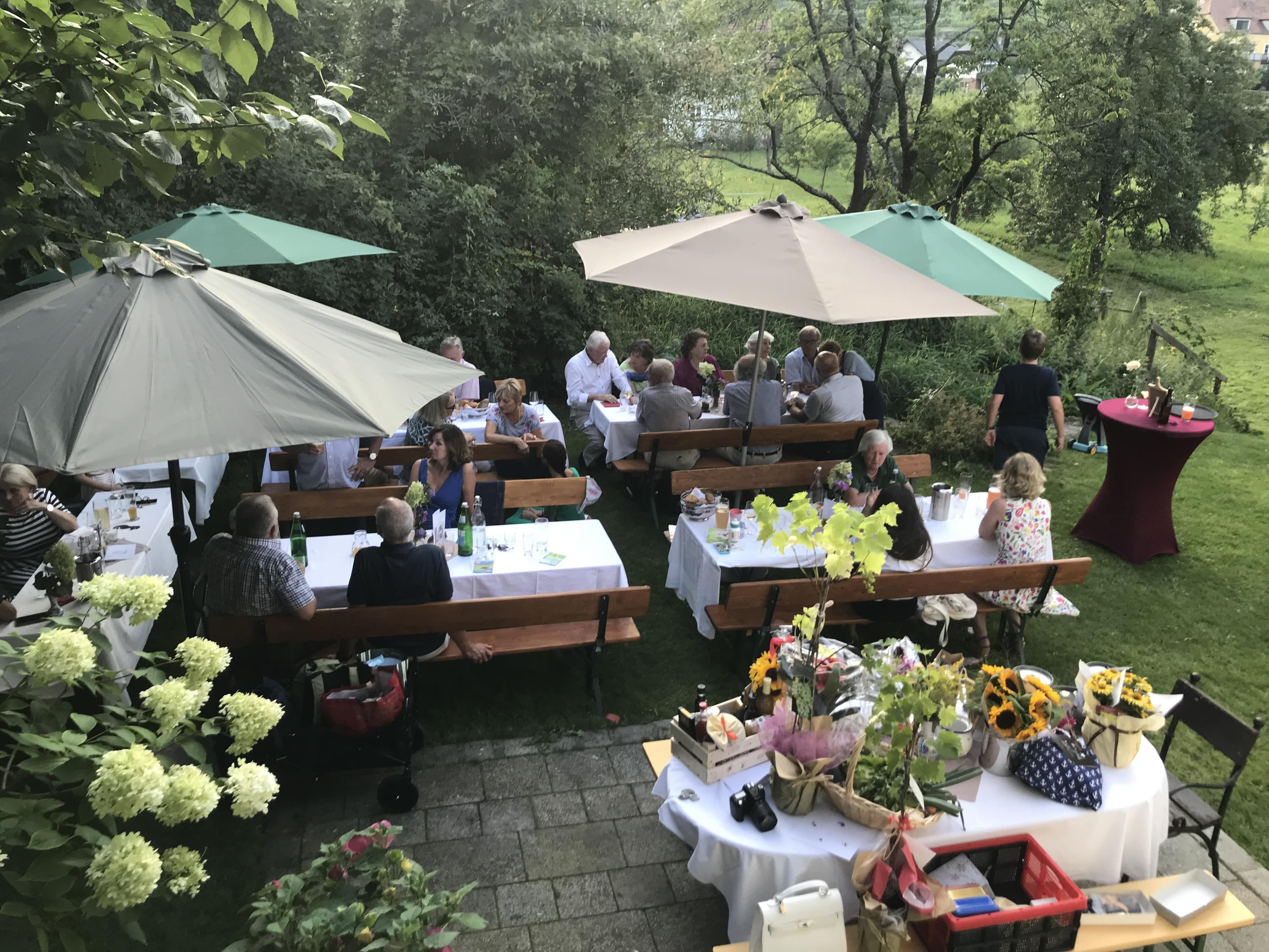 People sit at festively laid tables outside under parasols.