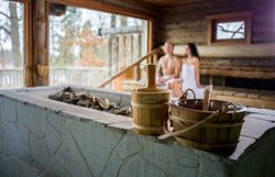 Modern hotel room with double bed, nature picture on the wall, armchair, table and floor lamp.