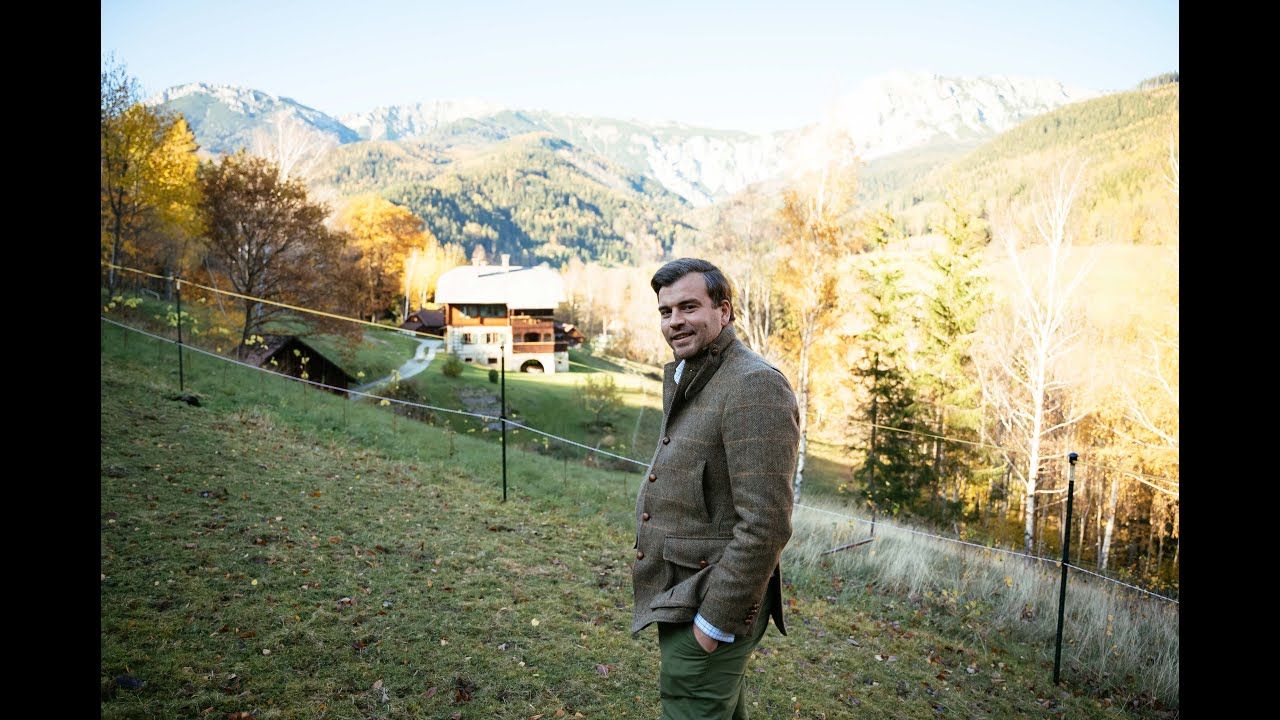 Man stands on a meadow and laughs into the camera