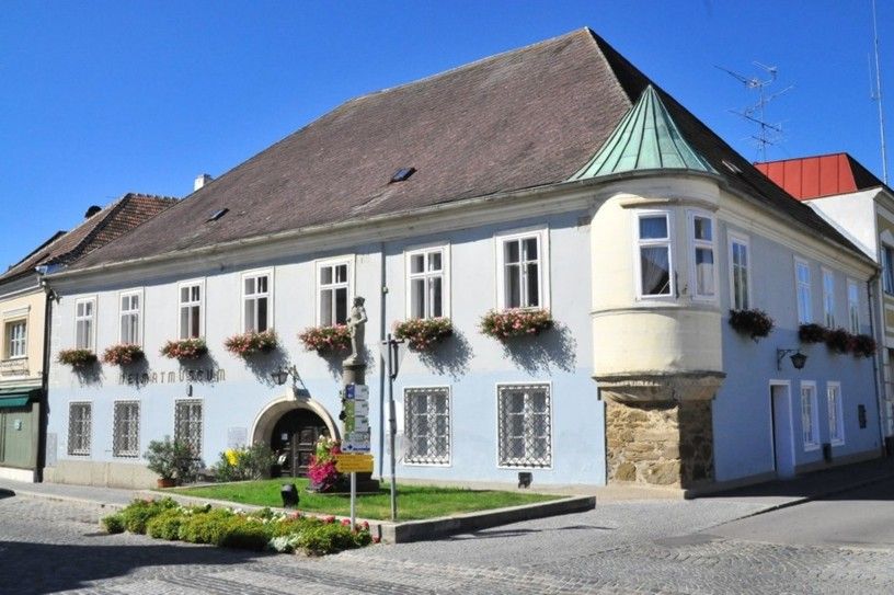 Historic building with blue façade and flower boxes, Langenlois local history museum.