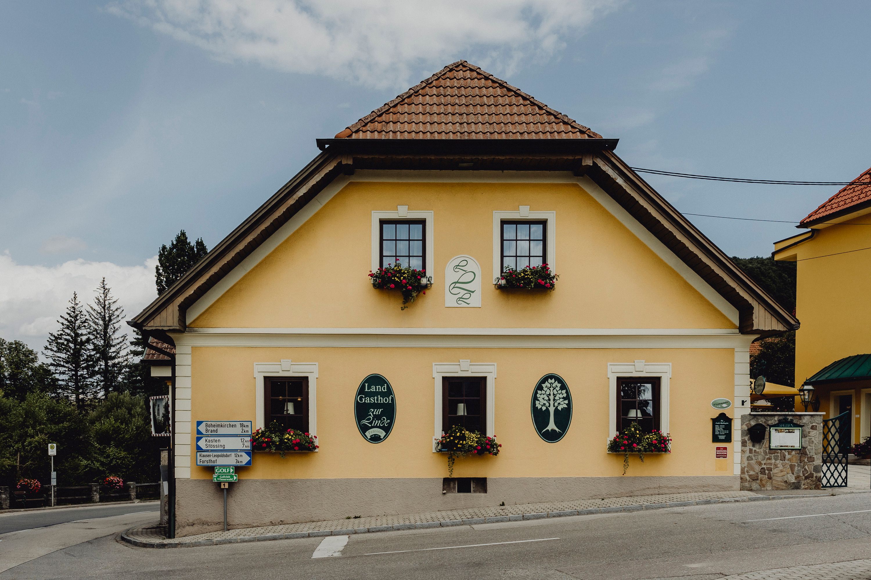 Yellow inn with flower boxes and signs on the façade.