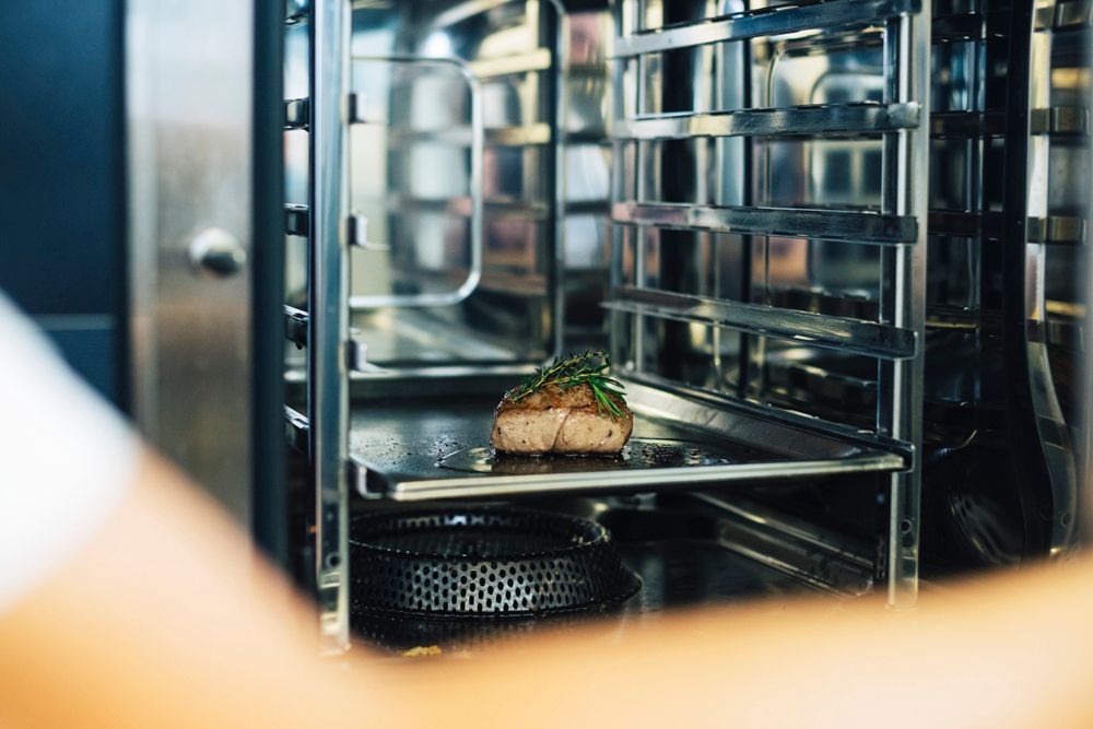 A piece of meat with herbs in a professional oven.