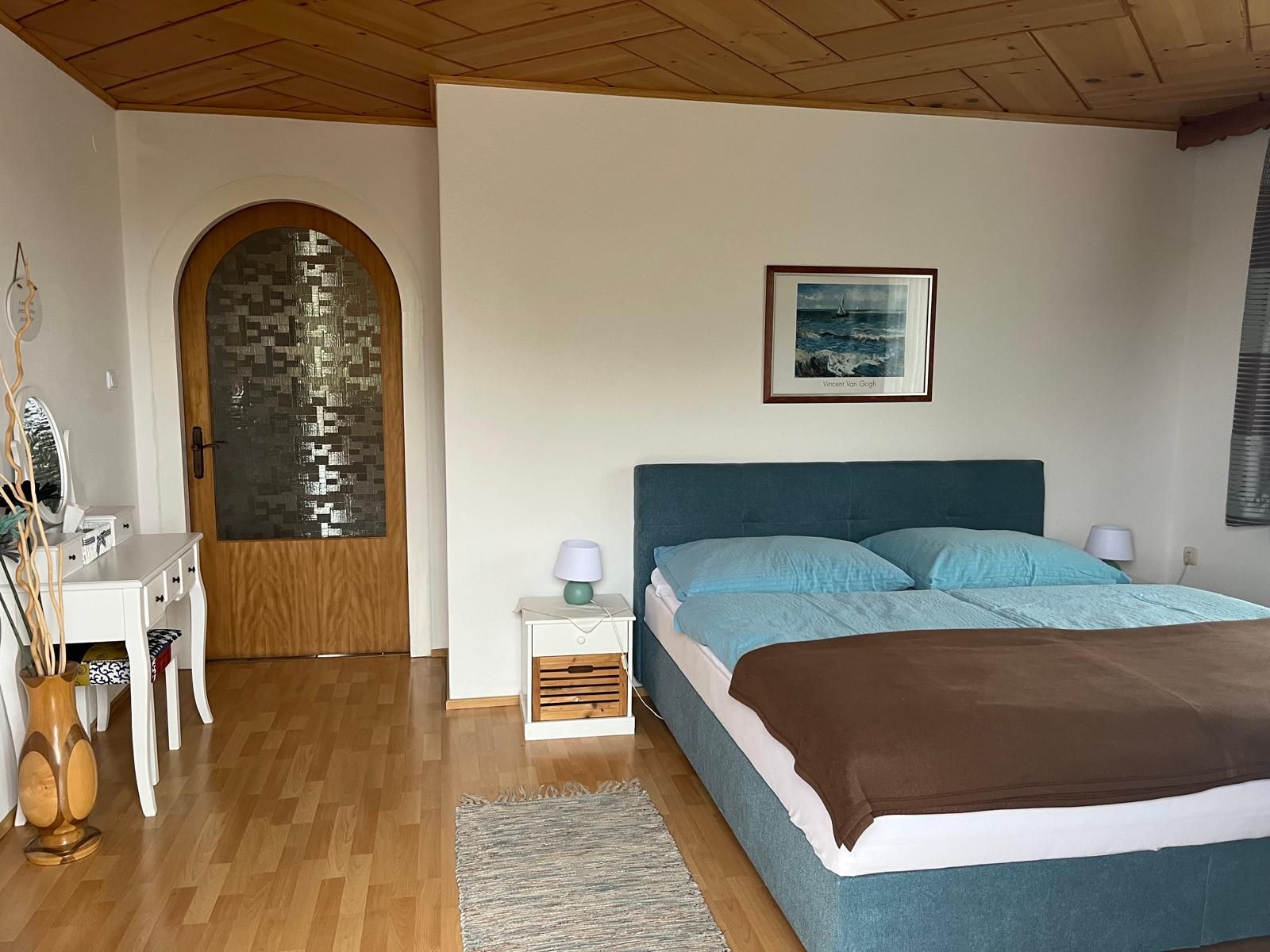 Bedroom with double bed, chest of drawers and wooden door.