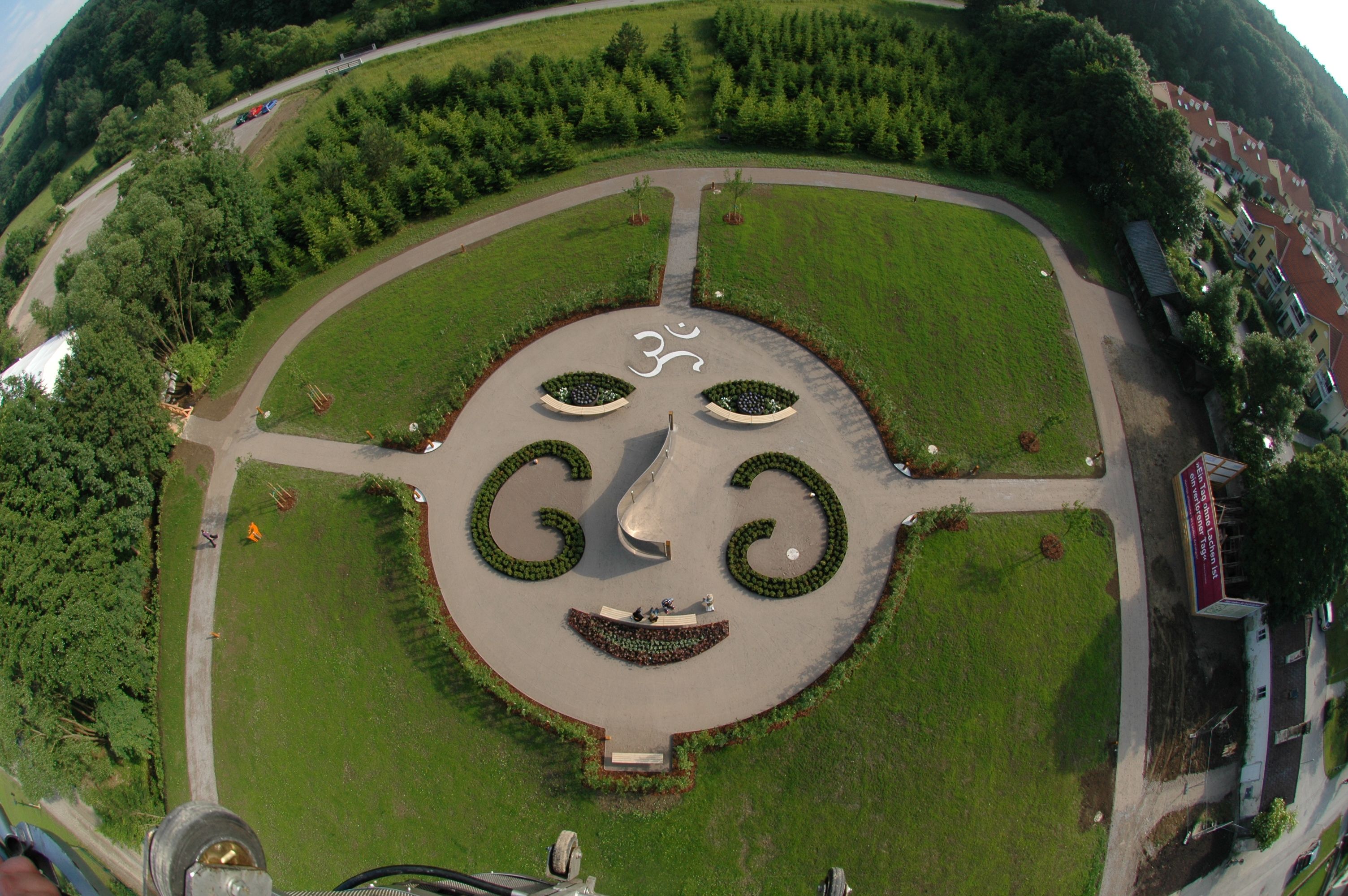 Aerial view of a garden with a facial pattern of plants and paths.
