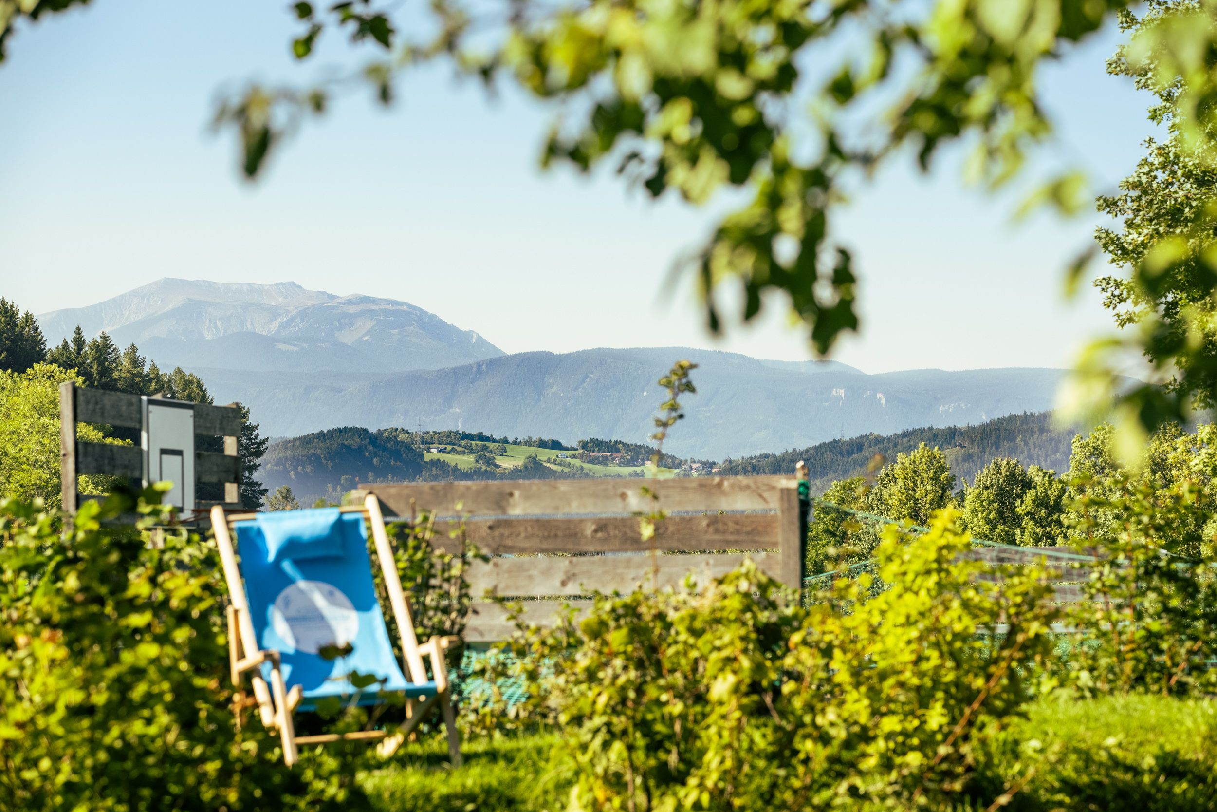 View from a garden onto a mountain landscape with a deckchair in the foreground.