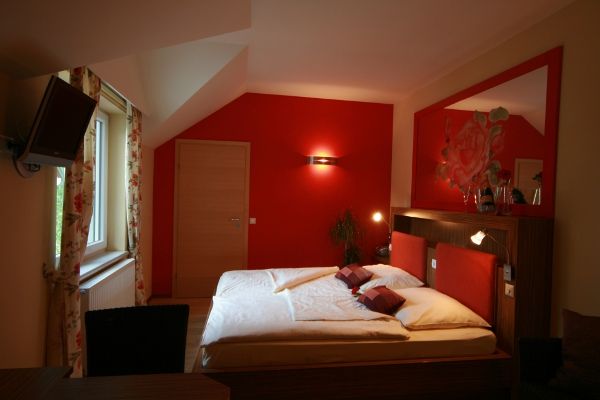 Cozy bedroom with red wall and double bed.